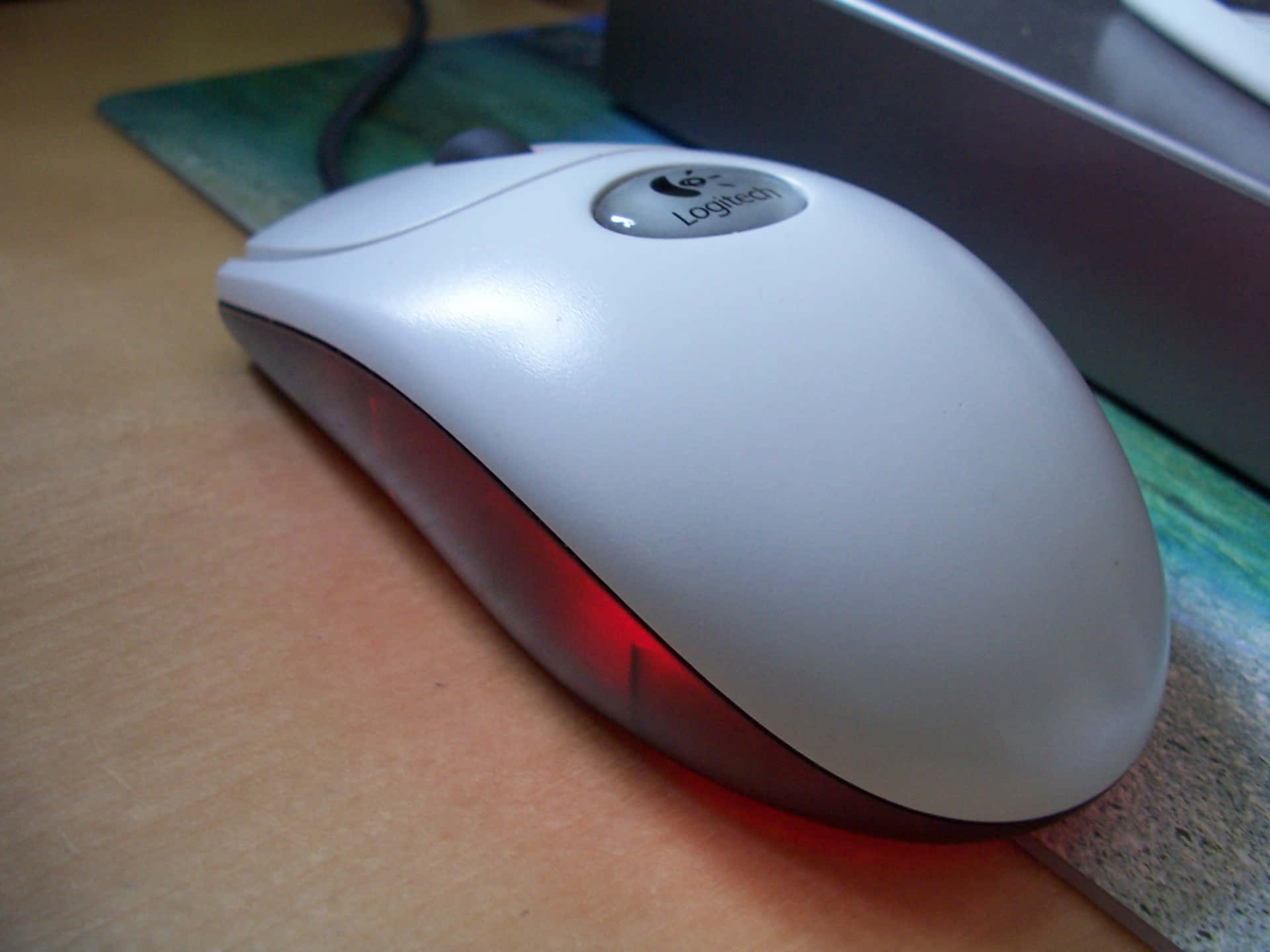 白色Logitech滑鼠，紅色光芒，木桌