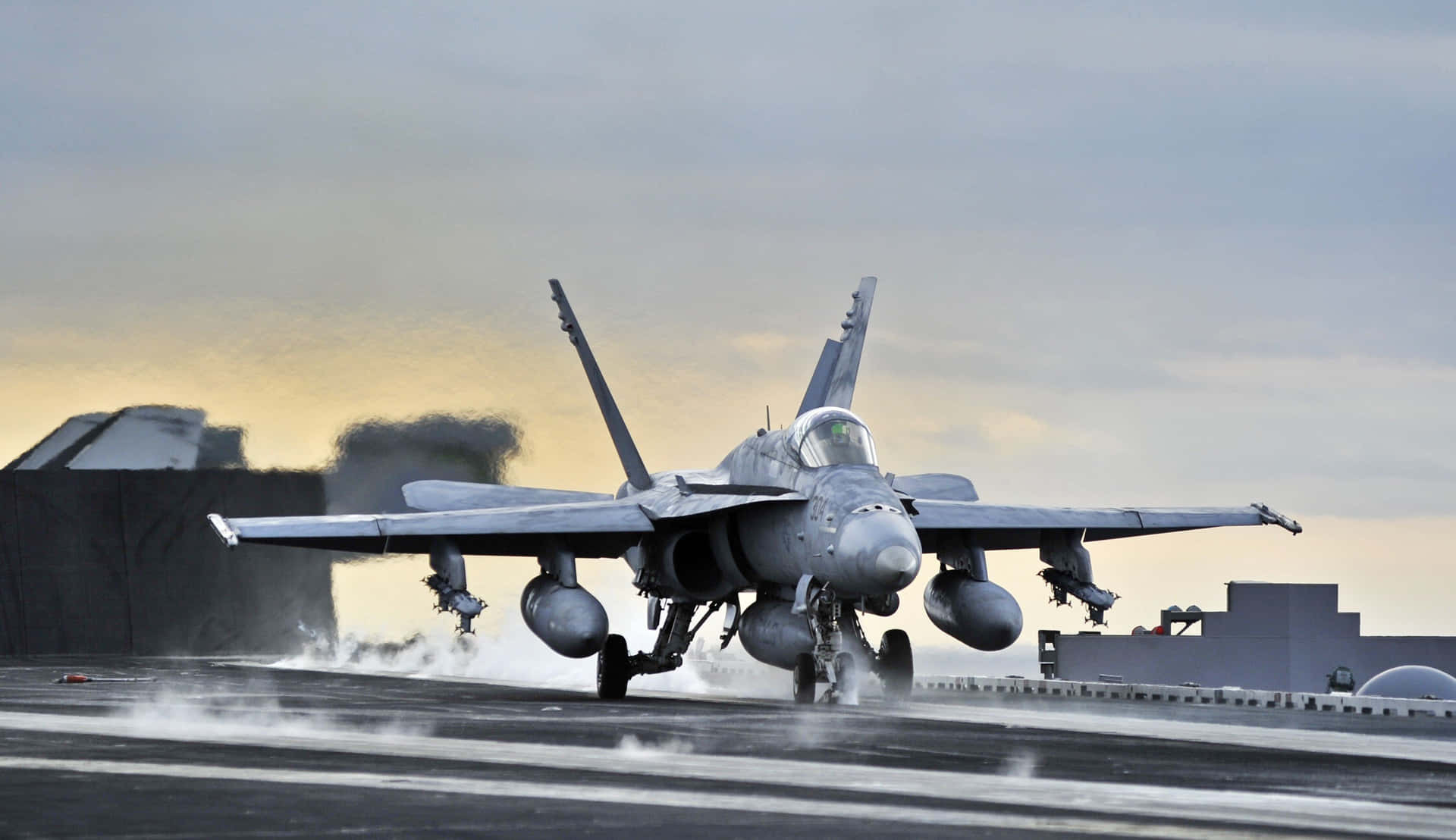 灰色戰鬥機在日落時從航空母艦起飛。