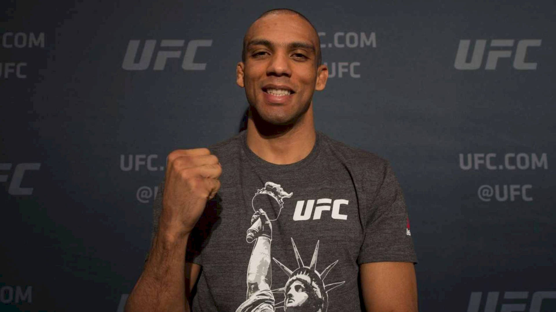 UFC拳手微笑並在品牌牆前舉起拳頭。