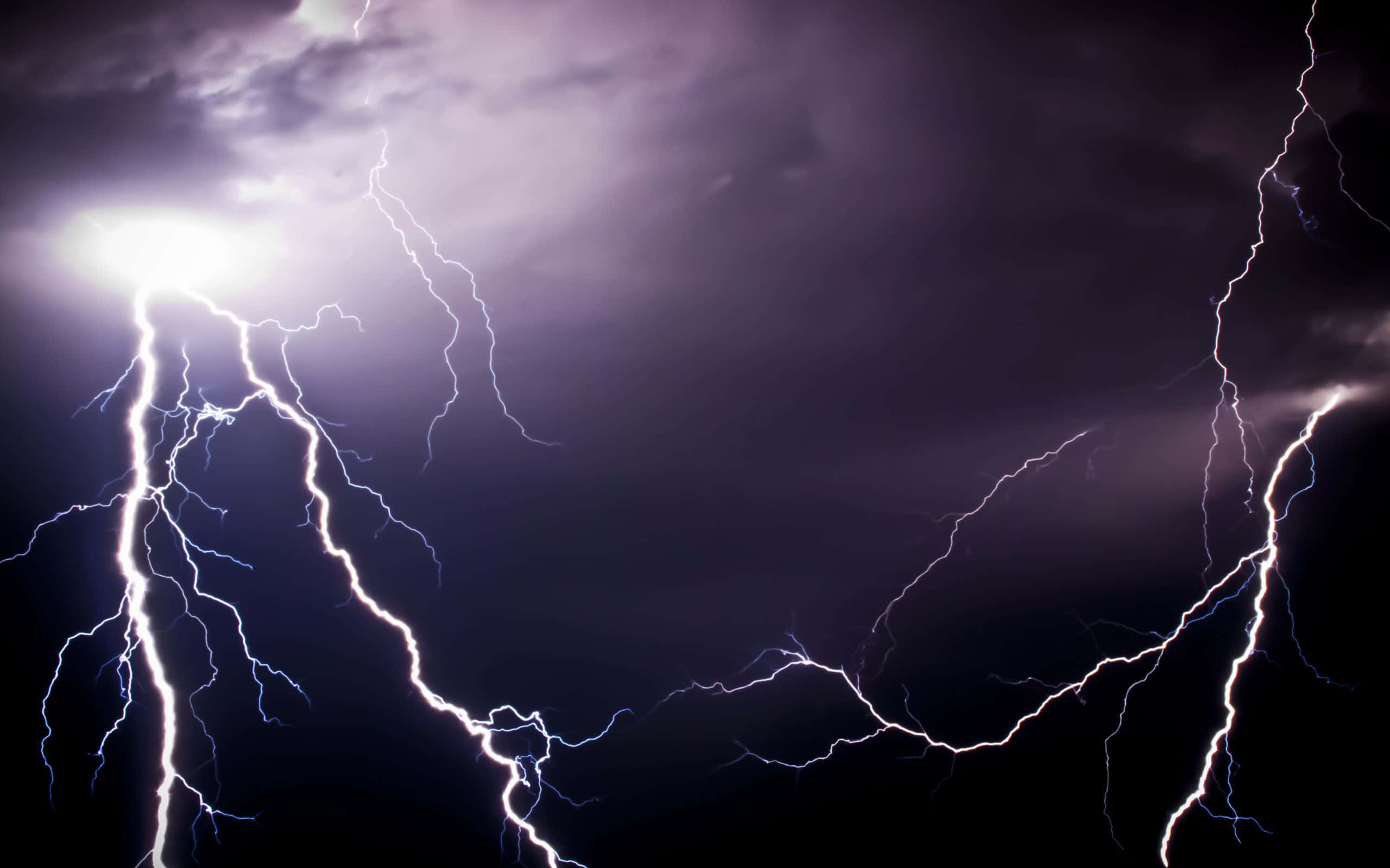 暴風 桌布 壁紙 — 強烈的閃電劃過黑暗的暴風雨天空，以電光般的白色和藍色閃光照亮紫色的雲層。