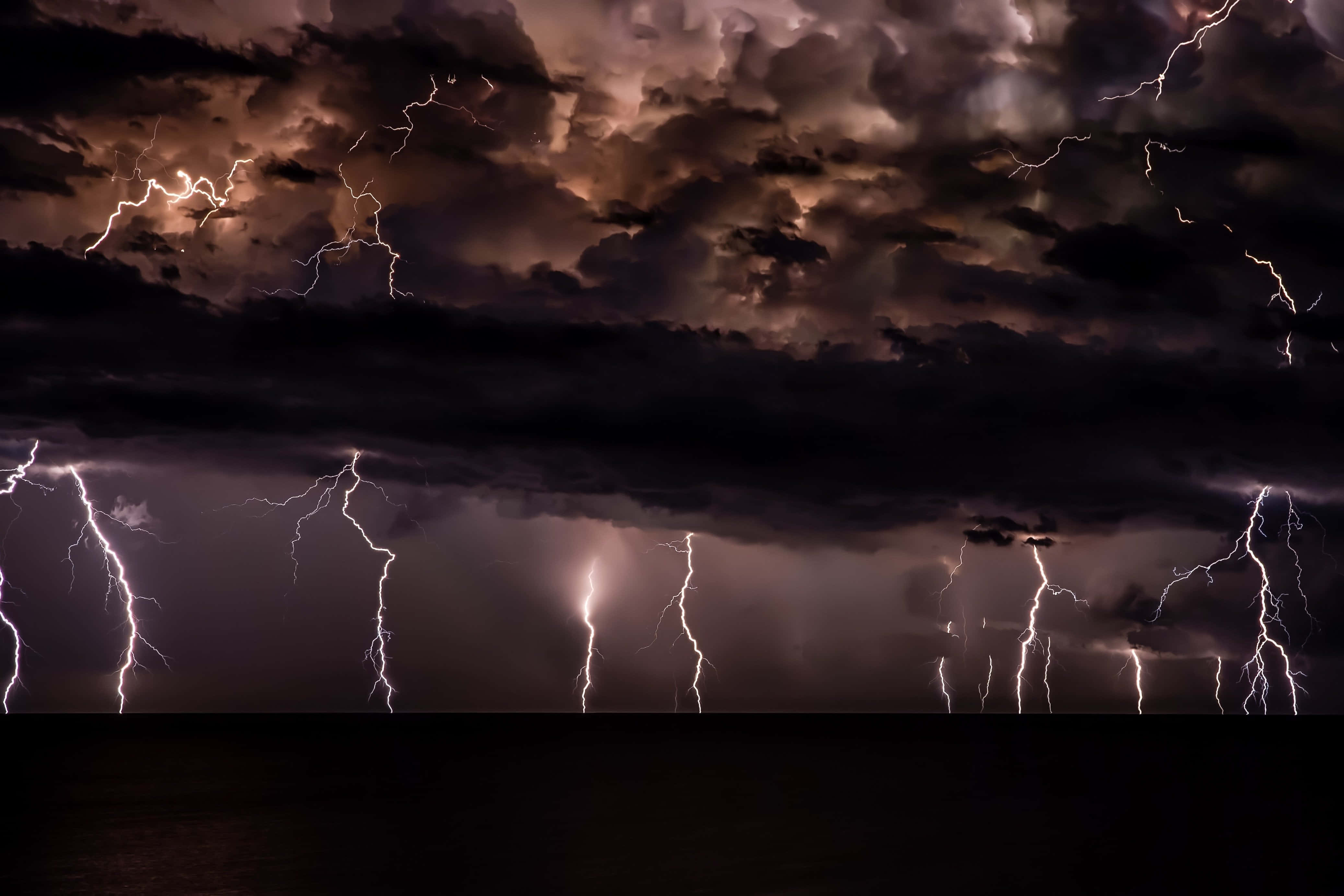Thunderstorm 桌布 壁紙 — 強烈的閃電在黑暗海洋上方的湍急暴風雨天空中劈啪作響。