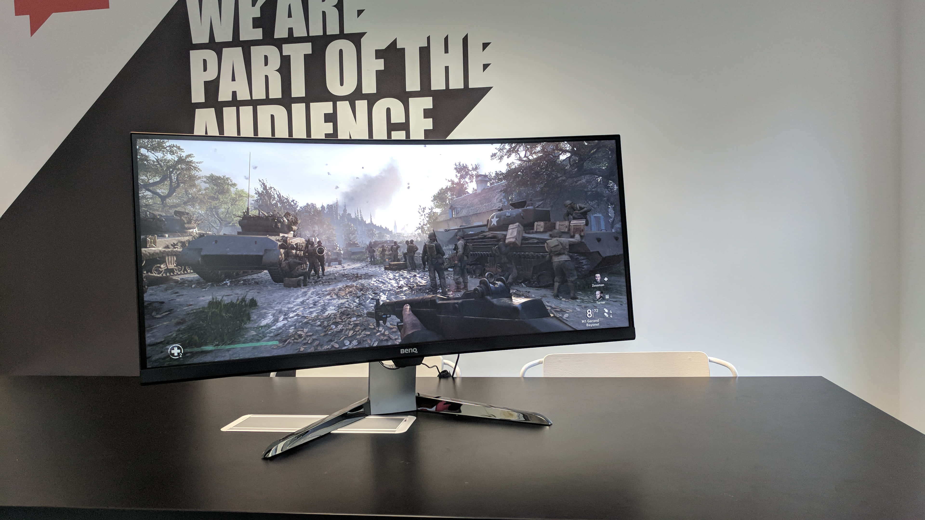 Gaming Monitors 桌布 壁紙 — 彎曲遊戲顯示器顯示煙霧彌漫的天空下，坦克和士兵在戰場上的場景。