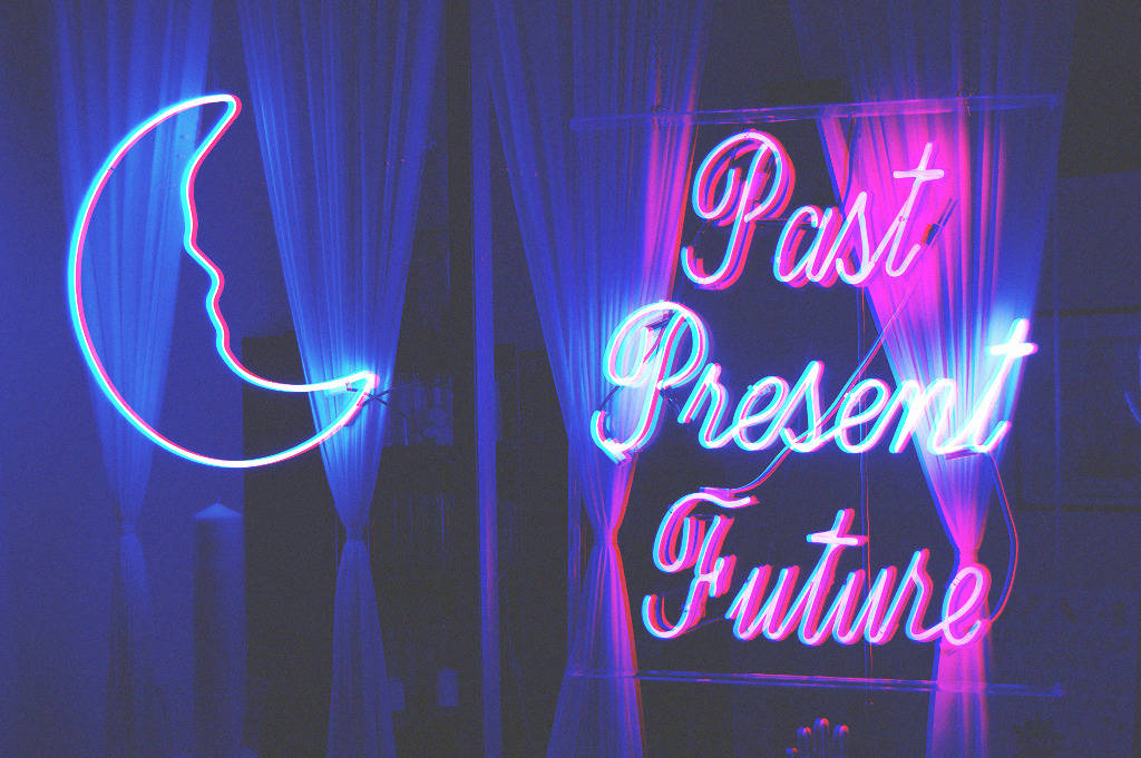 霓虹燈牌寫著 Past Present Future 和一個月亮形狀，以藍色和粉紅色發光。
