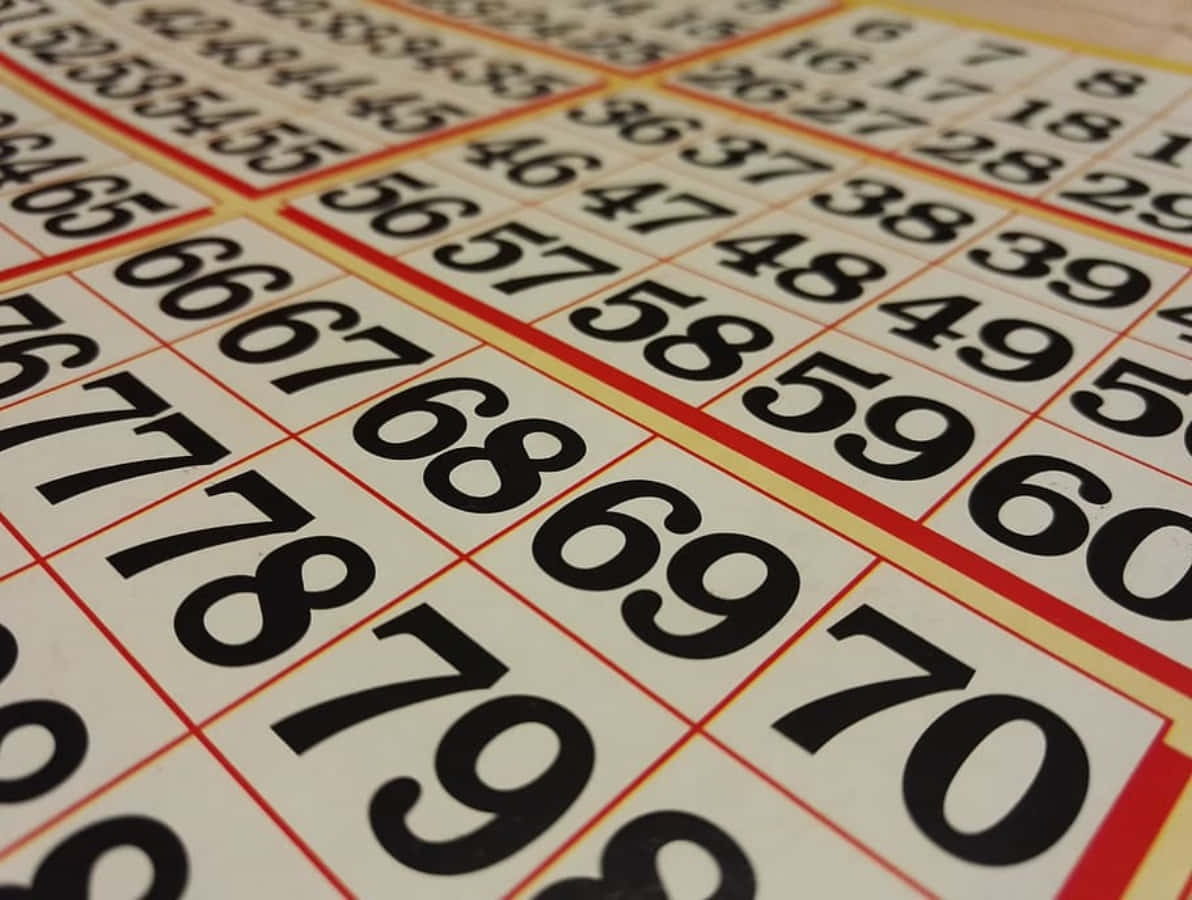 Bingo 桌布 壁紙 — 彩票網格的特寫，奶油色背景上有粗體黑色數字，並以紅色和黃色邊框框住。