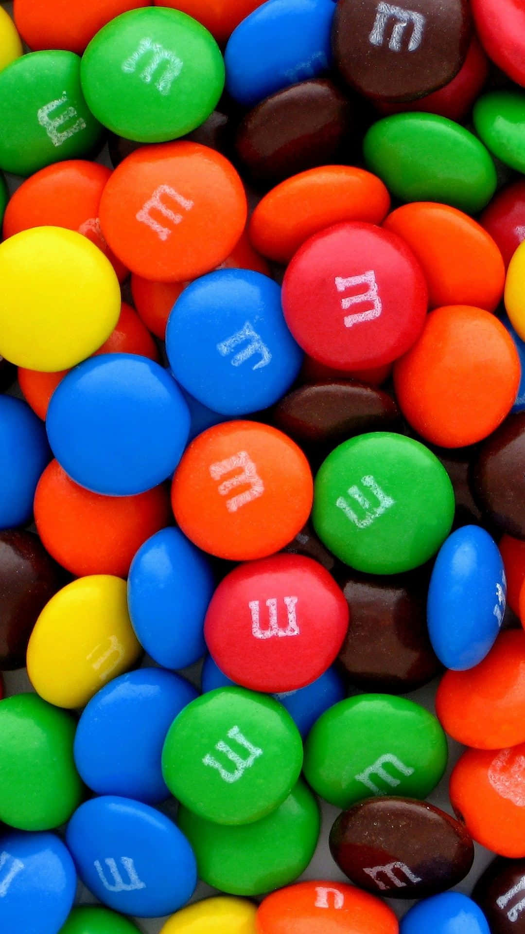 彩色M&M's巧克力豆安卓美食背景 壁紙 — 色彩繽紛的M&M's糖果特寫，白色「m」標誌密集散落。
