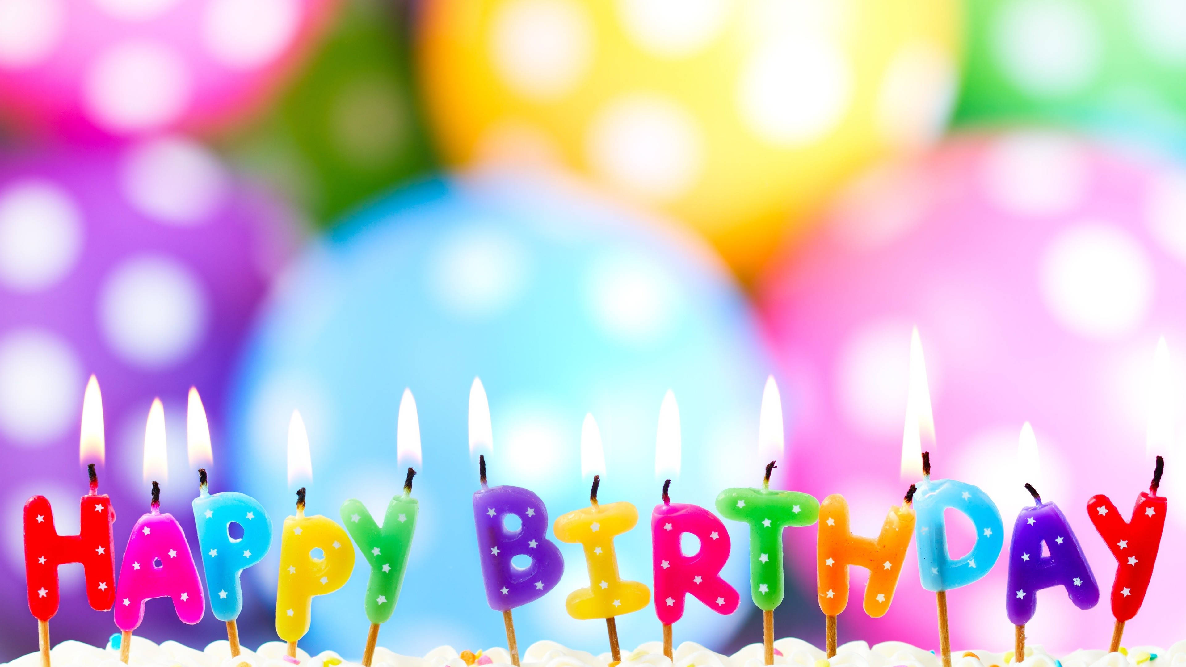 彩色氣球生日蛋糕蠟燭 壁紙 — 色彩繽紛的字母蠟燭在糖霜蛋糕上拼出 happy birthday，背景有模糊的波點氣球。