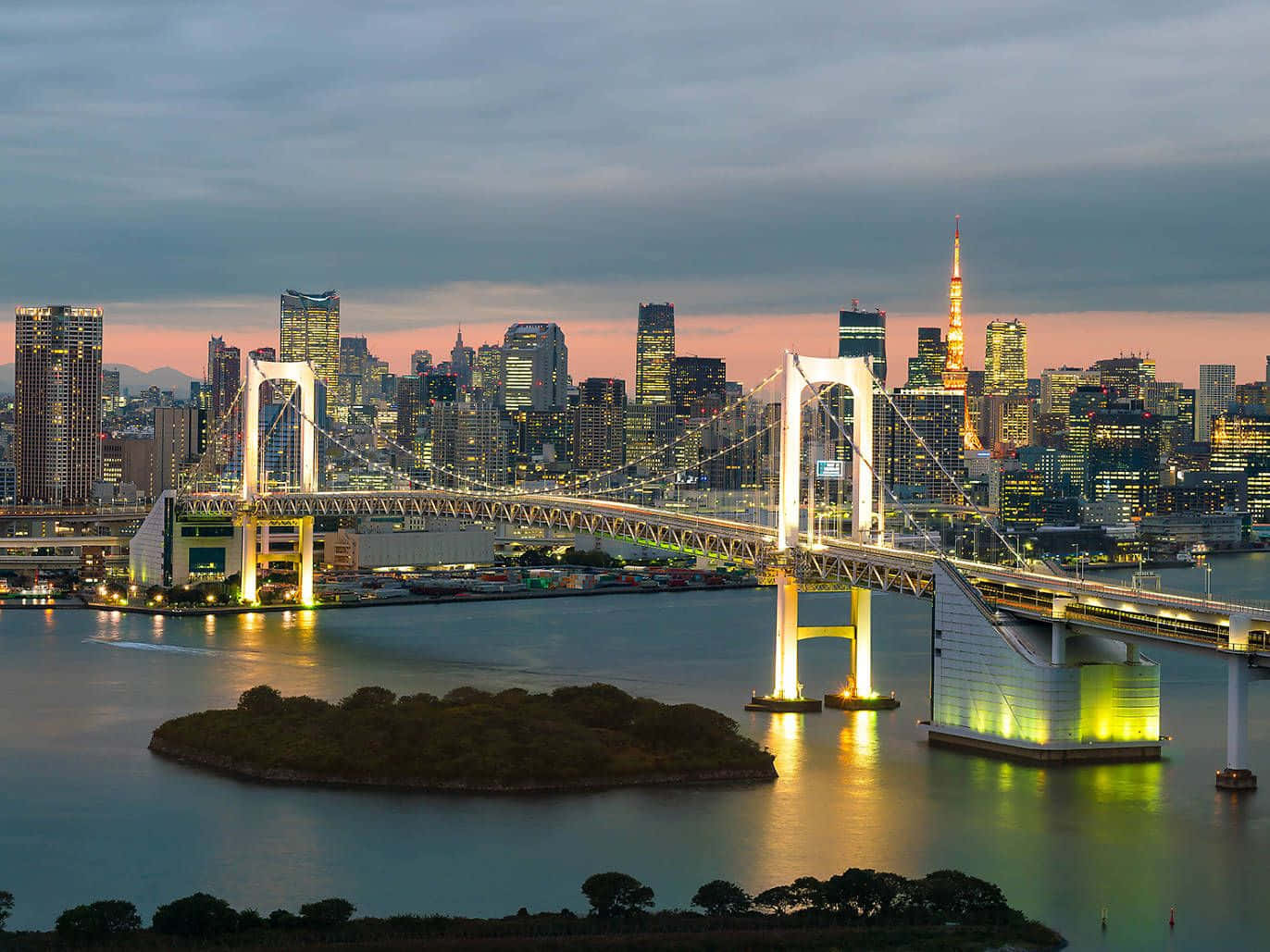 彩虹橋，令人屏息的美景！ 壁紙 — 彩虹橋在黃昏時分在東京灣上閃耀金光，城市燈光倒映在水面上，遠處的東京塔閃閃發光。