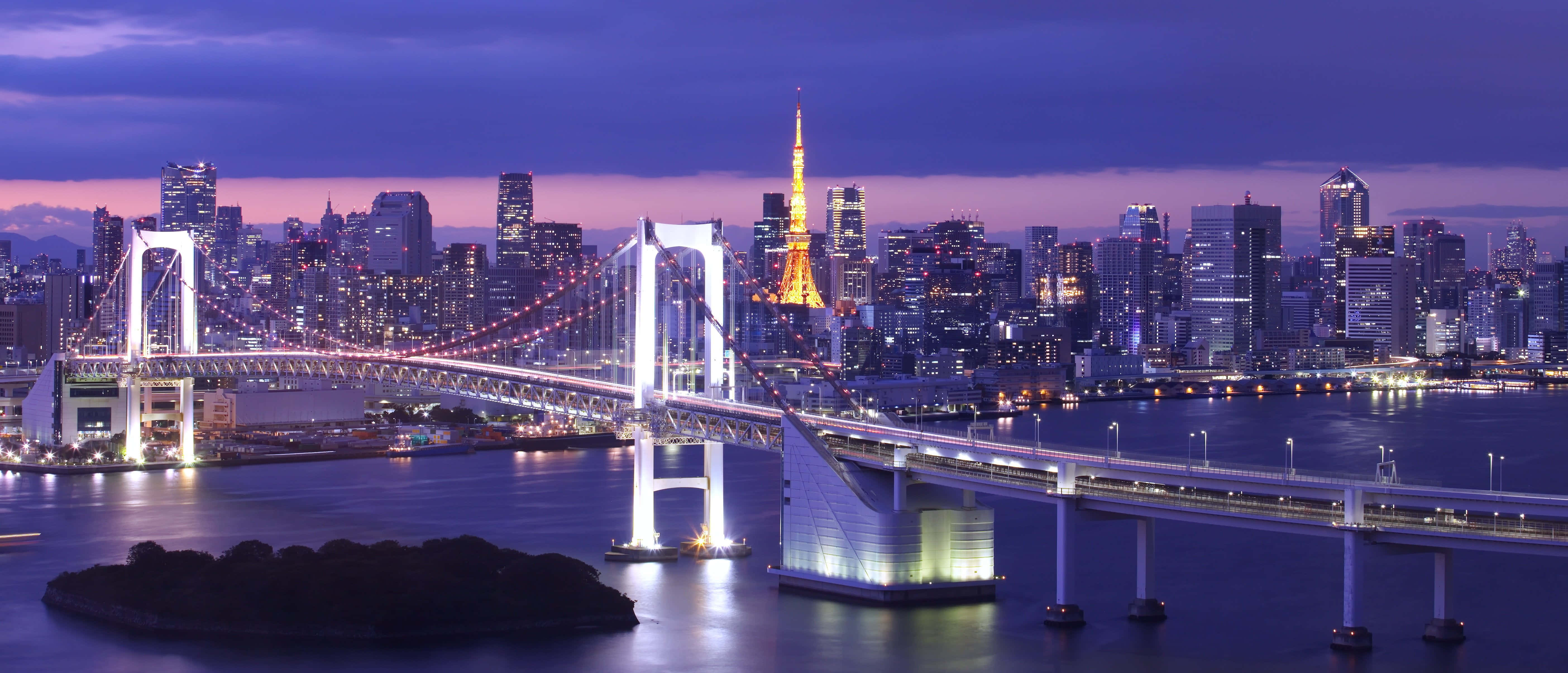 東京 桌布 壁紙 — 彩虹橋和東京塔在黃昏時照亮東京的天際線，充滿活力的城市燈光倒映在平靜的水面上。