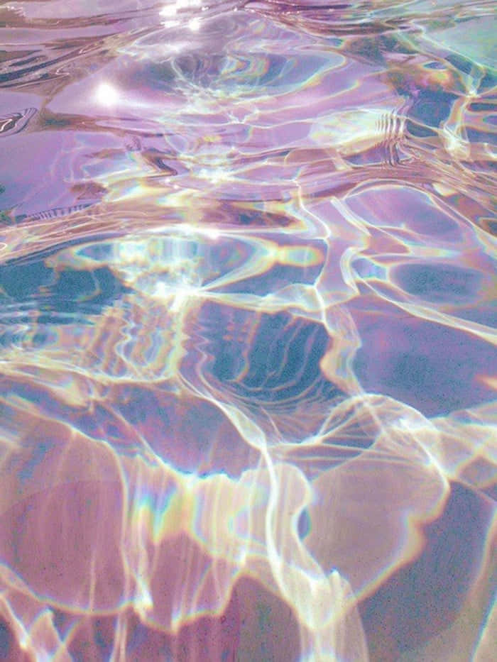 彩虹色水池 壁紙 — 彩虹色的水波在明亮的陽光下閃爍著粉紫、粉紅和金色的柔和色調，營造出夢幻般的抽象圖案。