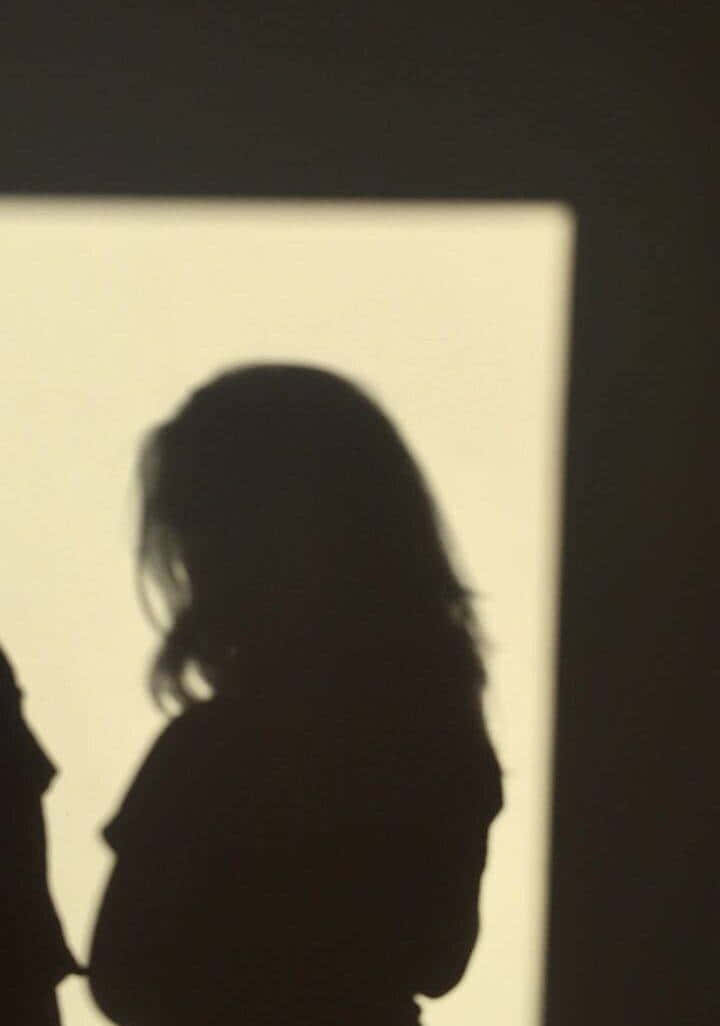 一個人在黑暗房間裡站在明亮窗戶旁的剪影。