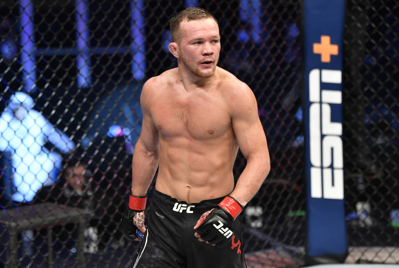一名赤裸上身的MMA拳手穿著UFC裝備，在八角籠內進行比賽。