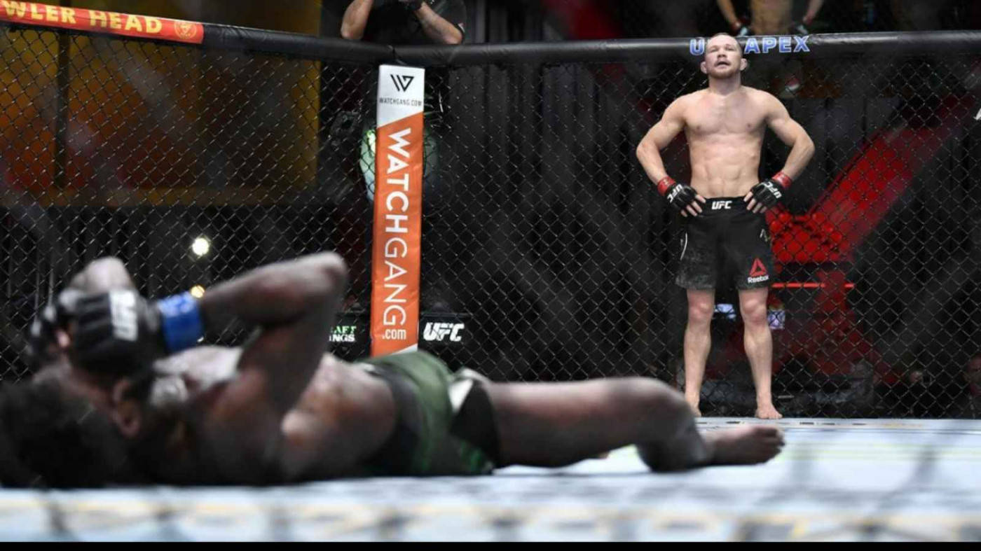 MMA拳手在八角籠內勝利地站在倒下的對手之上。