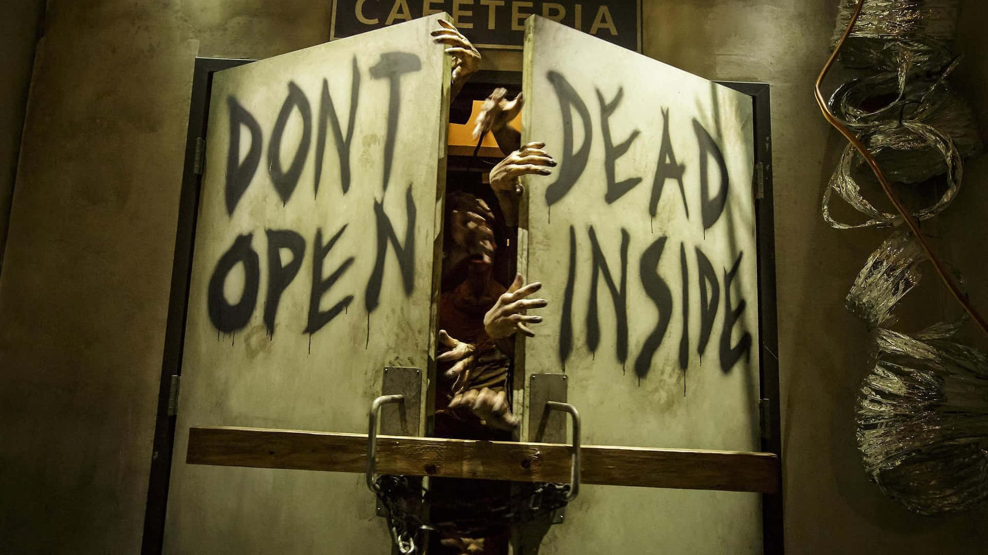 殭屍的手抓住一扇在自助餐廳裡帶有警告塗鴉的設有路障的門。