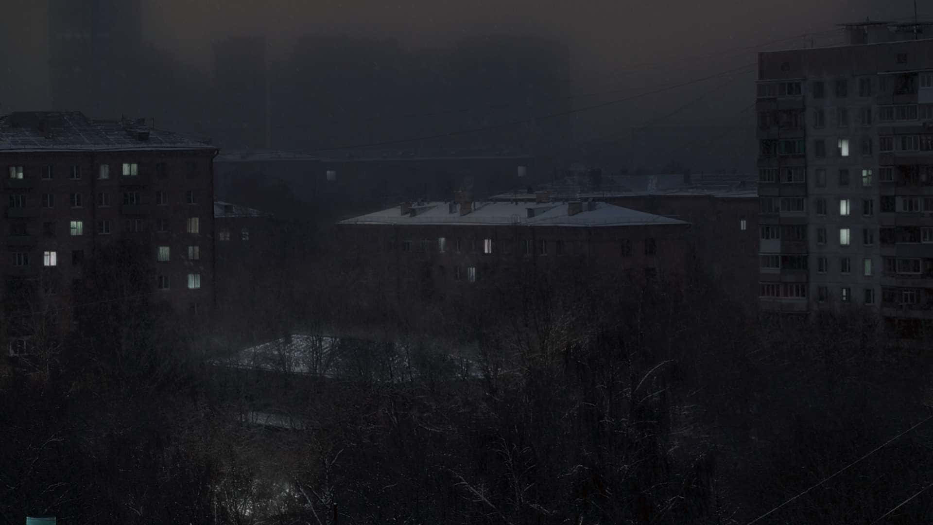 夜晚積雪的公寓大樓，在冬日霧氣中閃爍的窗戶。