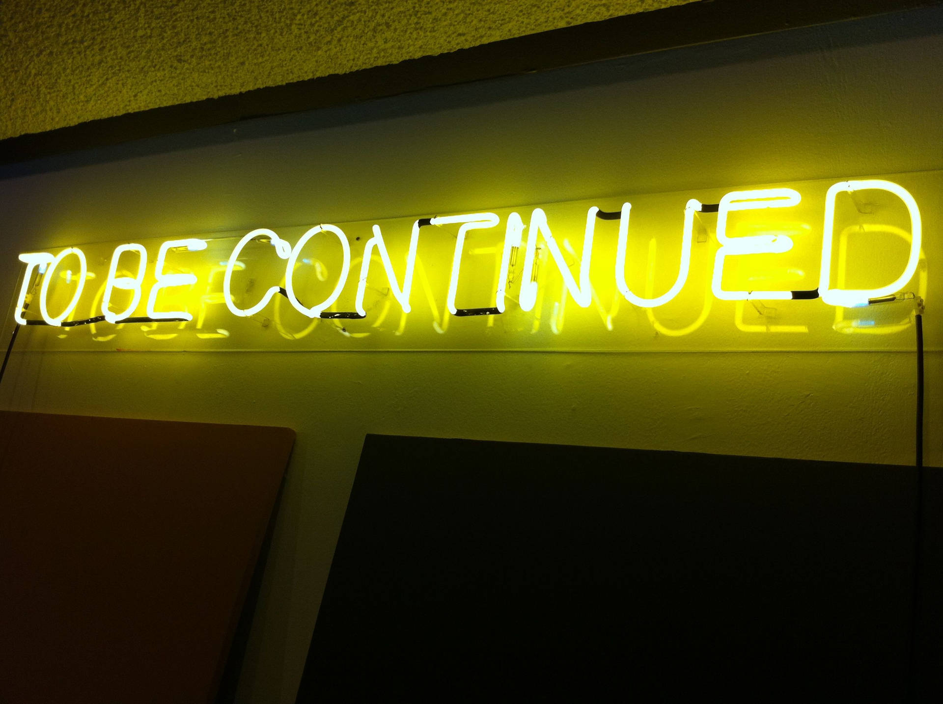 牆上黃色燈光寫著「to be continued」的霓虹燈牌。