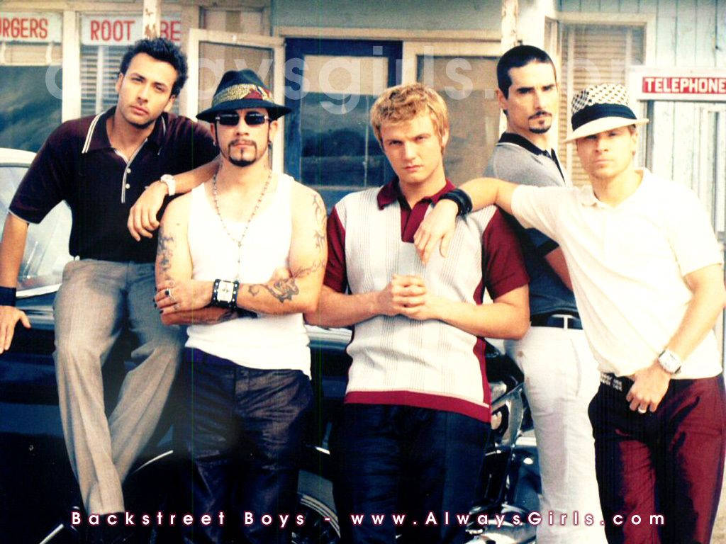 Backstreet Boys 在一個有復古汽車和復古標誌的餐廳前擺姿勢。