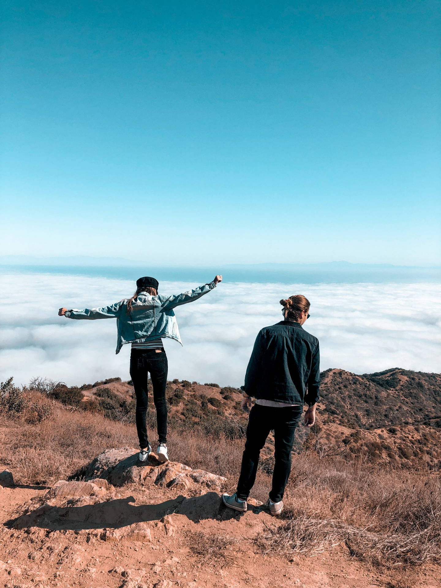 兩個人在雲端之上的山頂欣賞風景。