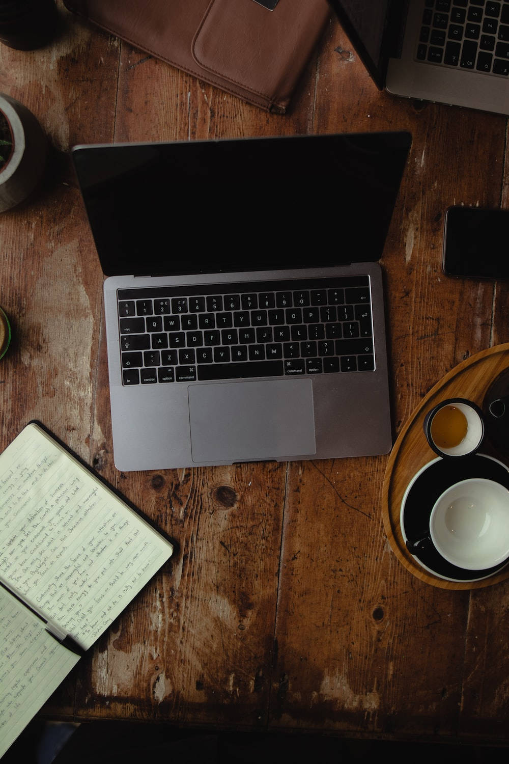 Best Laptop 桌布 壁紙 — 從上方俯瞰，一部銀色手提電腦放在質樸的木桌上，旁邊有筆記本、咖啡和電話。