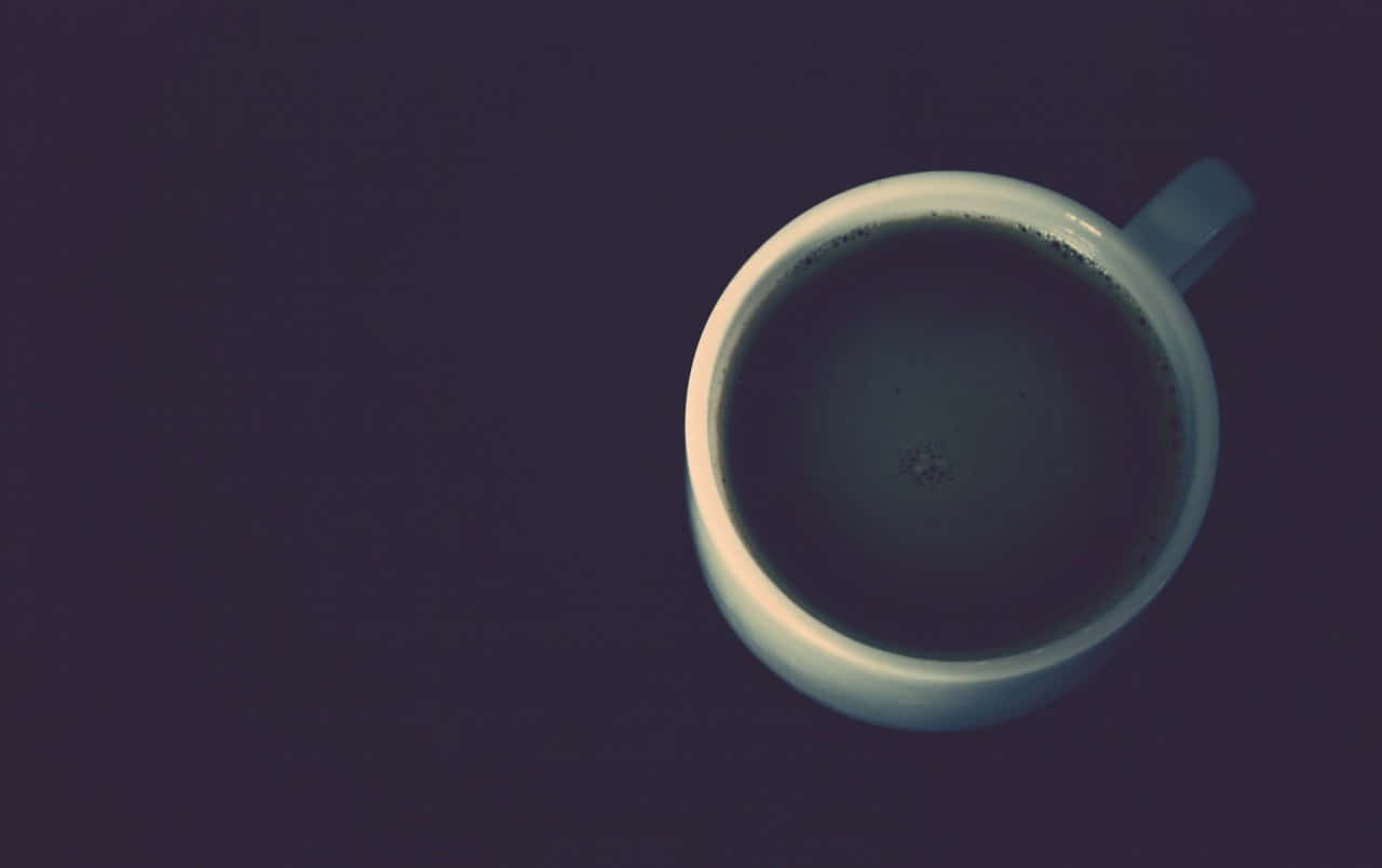 Black Coffee 桌布 壁紙 — 從上方俯瞰一個白色陶瓷杯，裝滿深色咖啡，背景為深紫色。