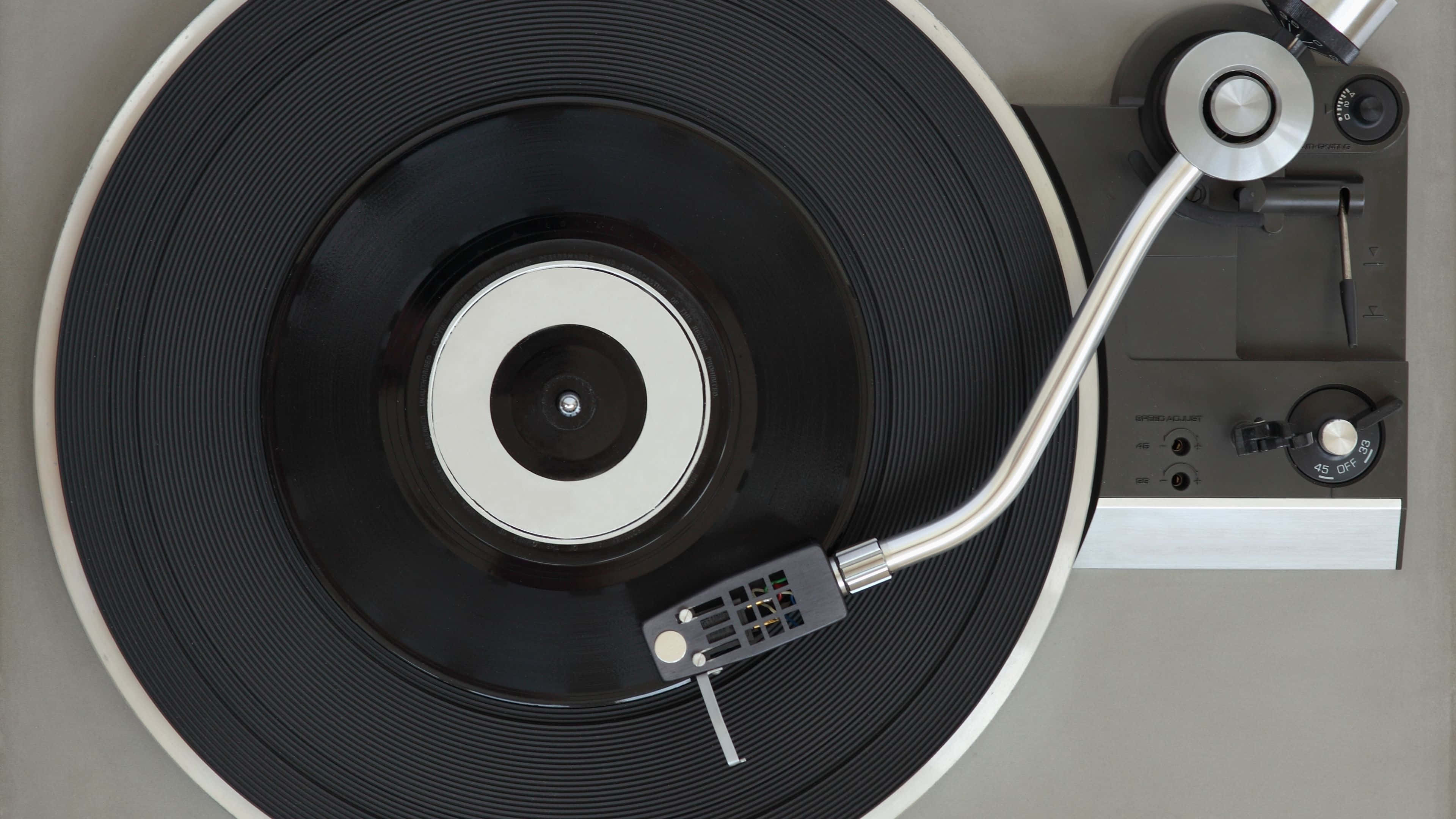 record 桌布 壁紙 — 從上方俯瞰一部復古黑膠唱盤，黑色黑膠唱片在銀色唱臂下轉動。
