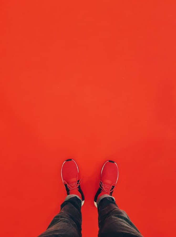 Red Shoes 桌布 壁紙 — 從上方俯瞰一雙穿著紅色運動鞋的腳站在純紅色地板上，構圖簡約。