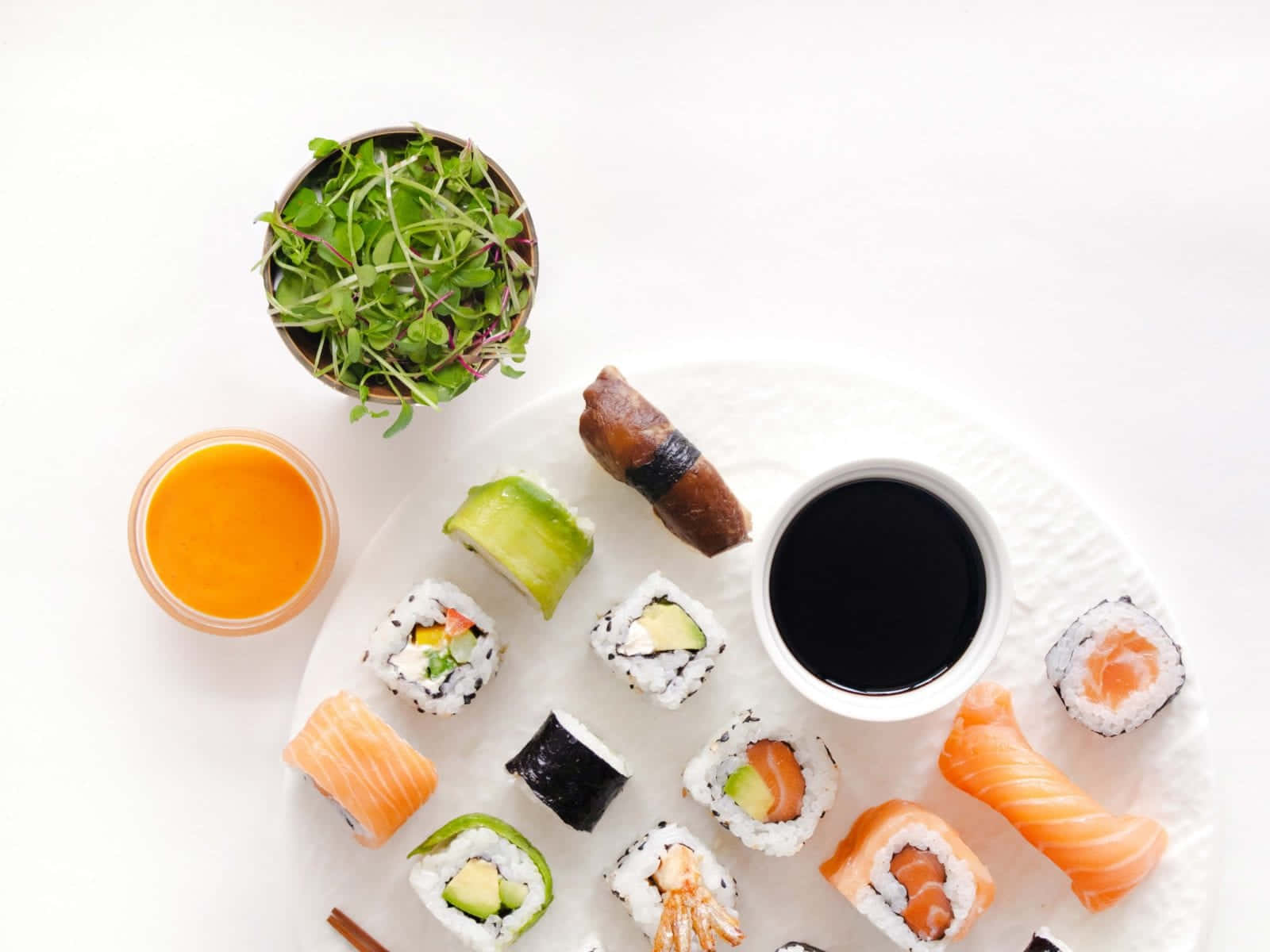 Sushi 桌布 壁紙 — 從上方俯瞰各種壽司卷和刺身擺放在白色碟子上，配以醬油和芥末。