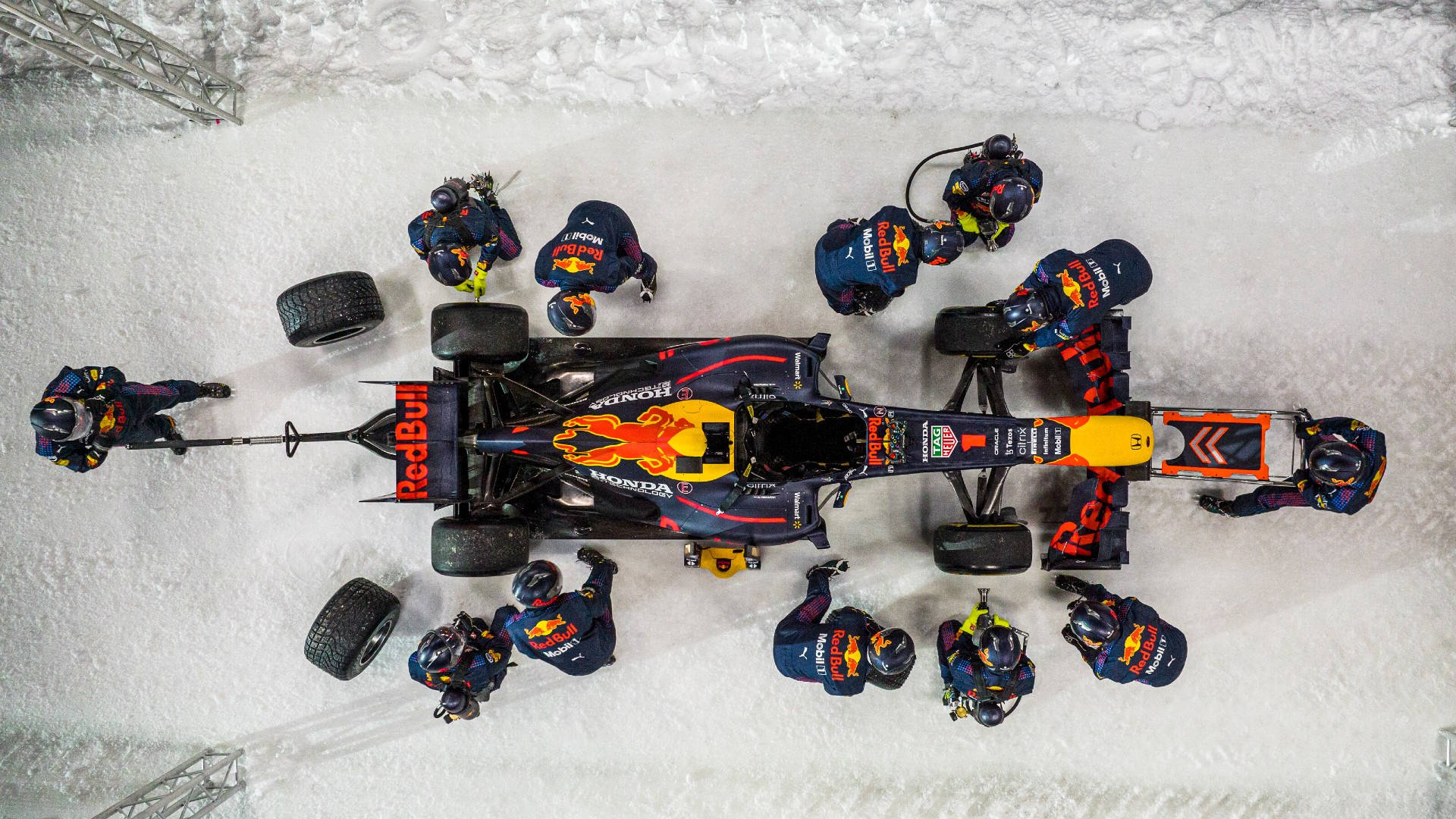 F1 桌布 壁紙 — 從上方俯瞰紅牛一級方程式車隊在雪地賽道上維修賽車，工作人員身穿藍色制服。