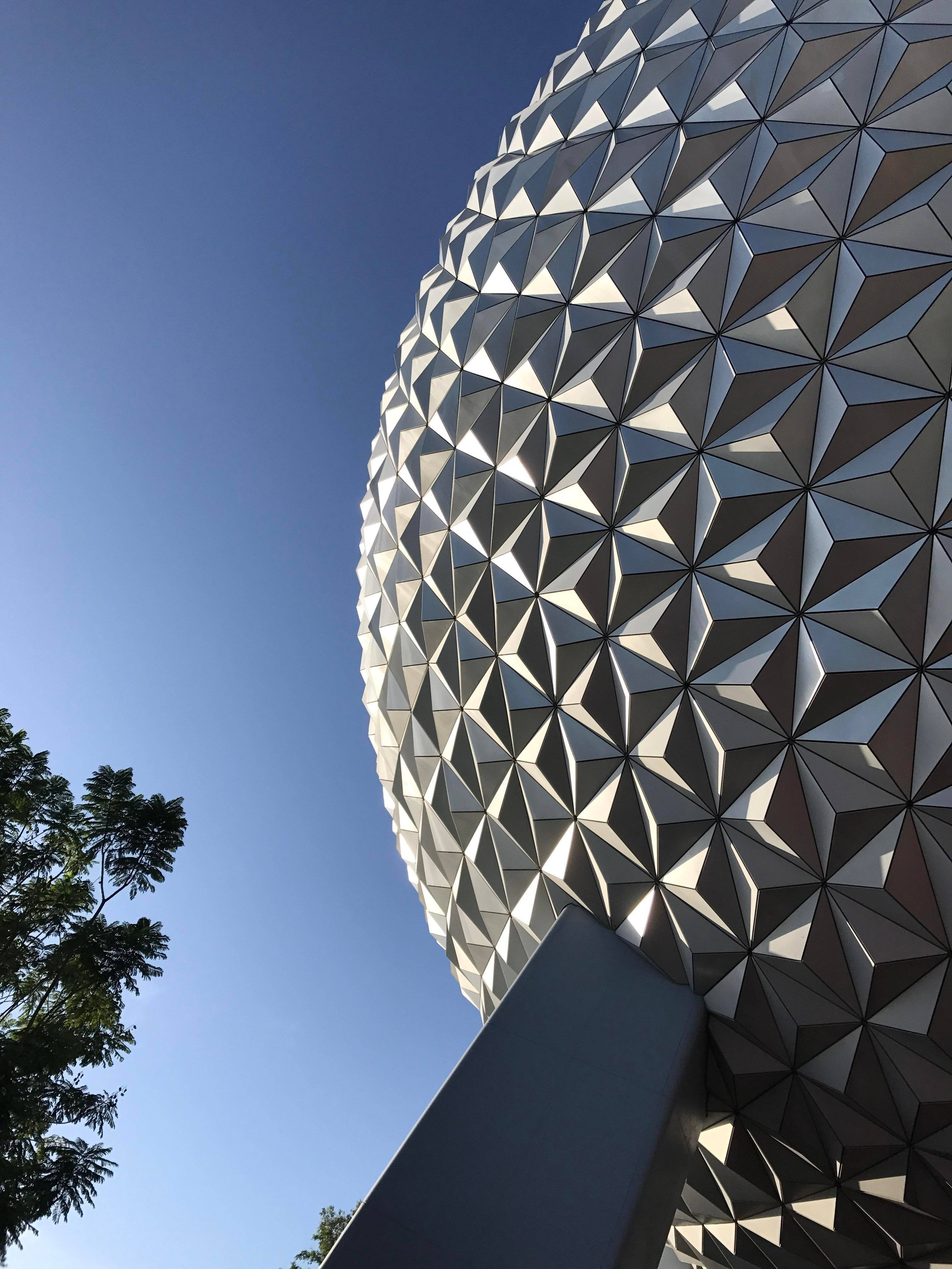 從下方仰拍的經典 Epcot 球體 壁紙 — 低角度拍攝標誌性測地線球體，尖銳三角形面板在清澈藍天下反射陽光。