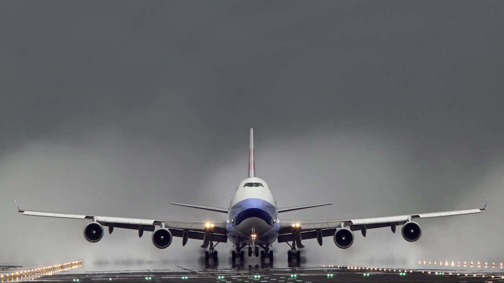一架大型飛機在暴風雨的天空下降落在潮濕的跑道上。