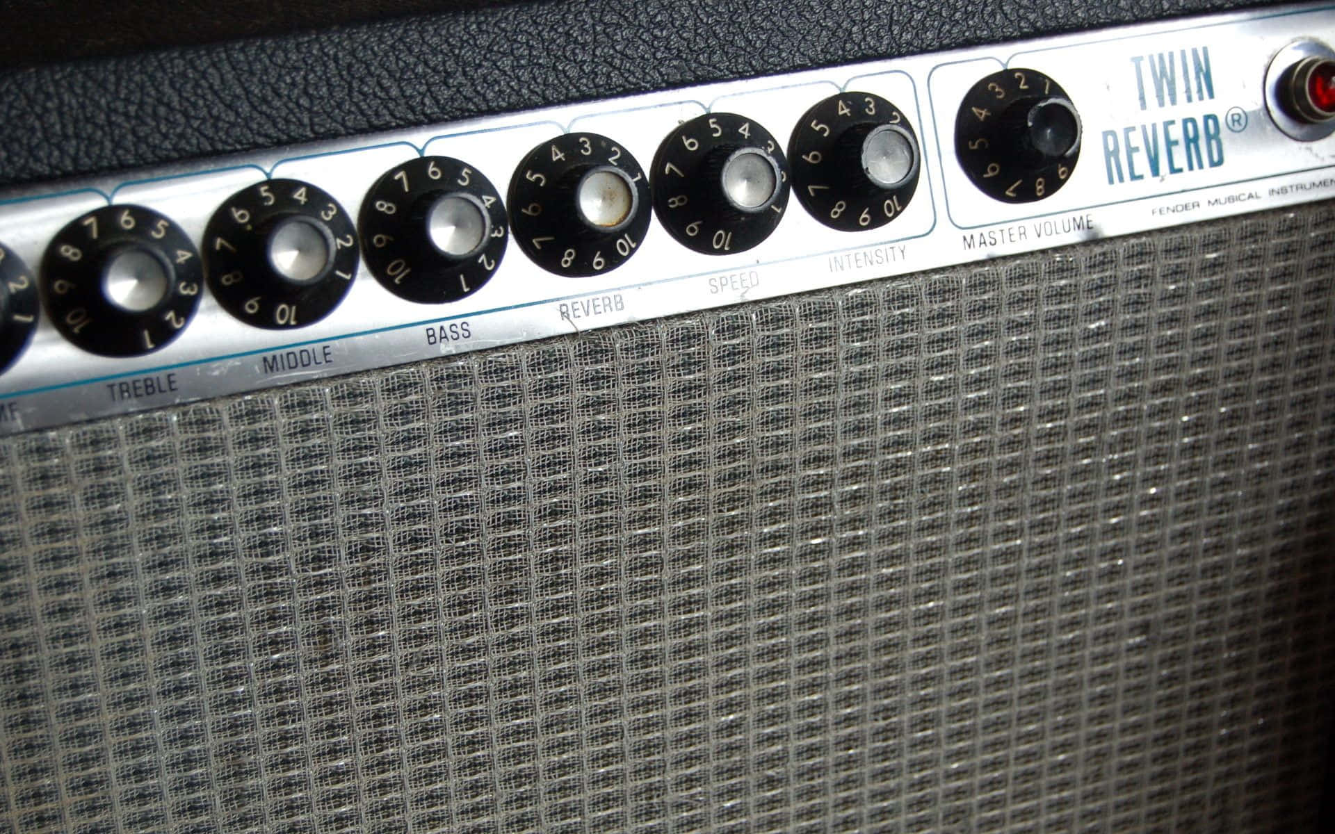 從你的吉他擴大機中獲得最佳音色 壁紙 — 復古Fender Twin Reverb結他擴音器特寫，帶有銀色網罩和標示高音、低音、混響的黑色旋鈕。