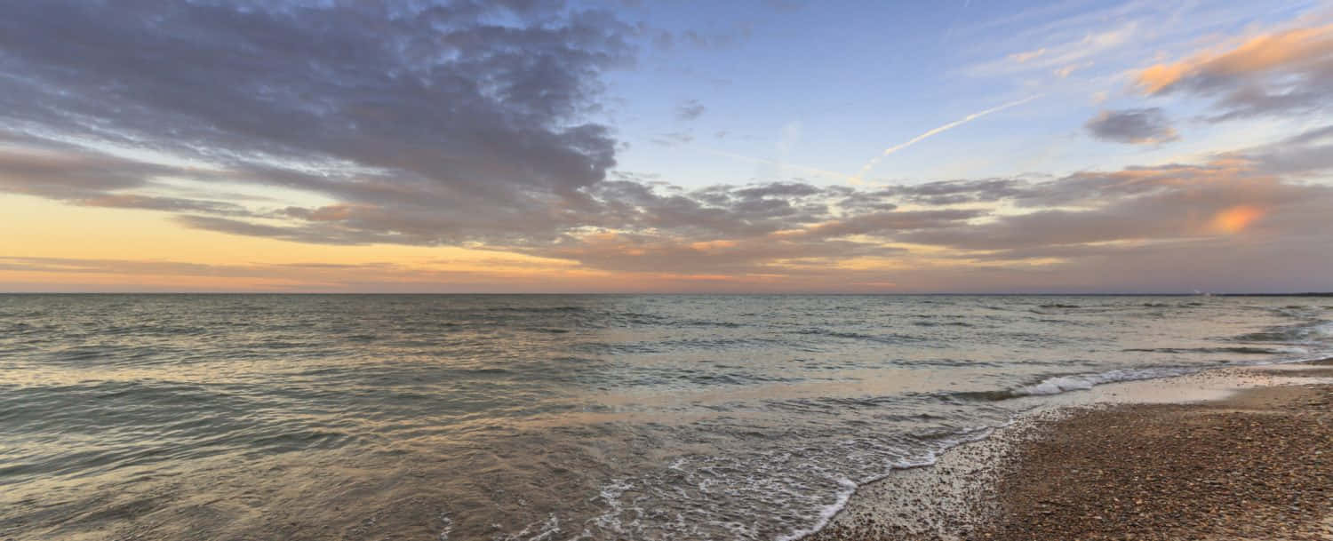 海洋上的夕陽，卵石海灘上的海浪