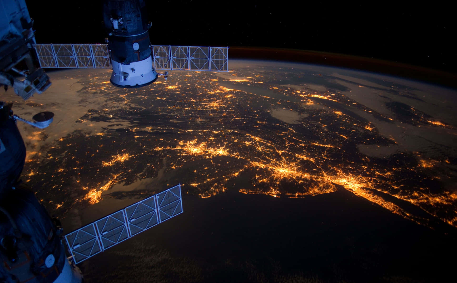 nasa 桌布 壁紙 — 從國際太空站看到的壯麗景色，顯示了夜間地球發光的城市燈光，映襯著黑暗的海洋和陸地。