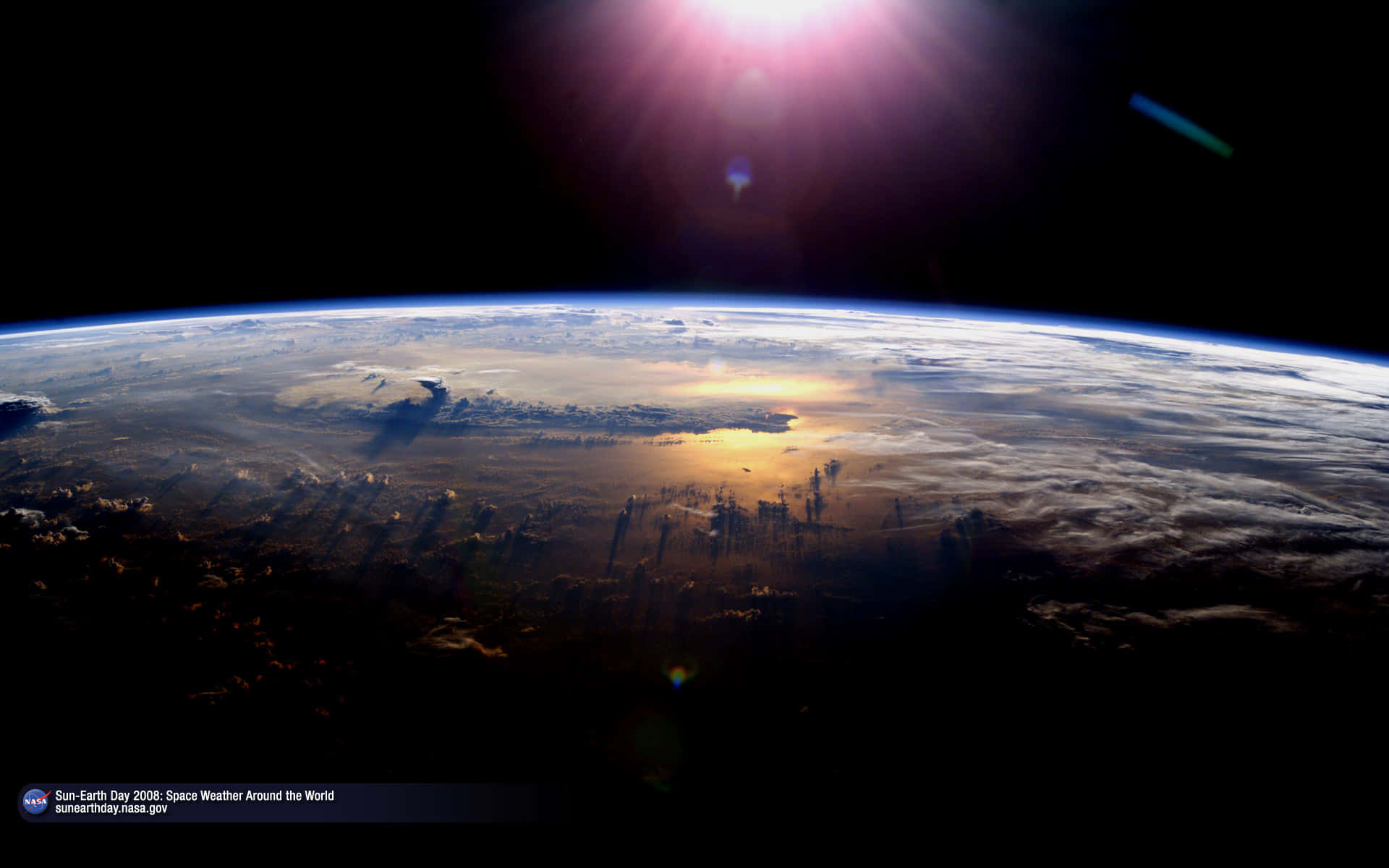 從外太空俯瞰地球的壯麗景色 壁紙 — 從太空觀看地球，日出時太陽耀斑照亮雲層和海洋。