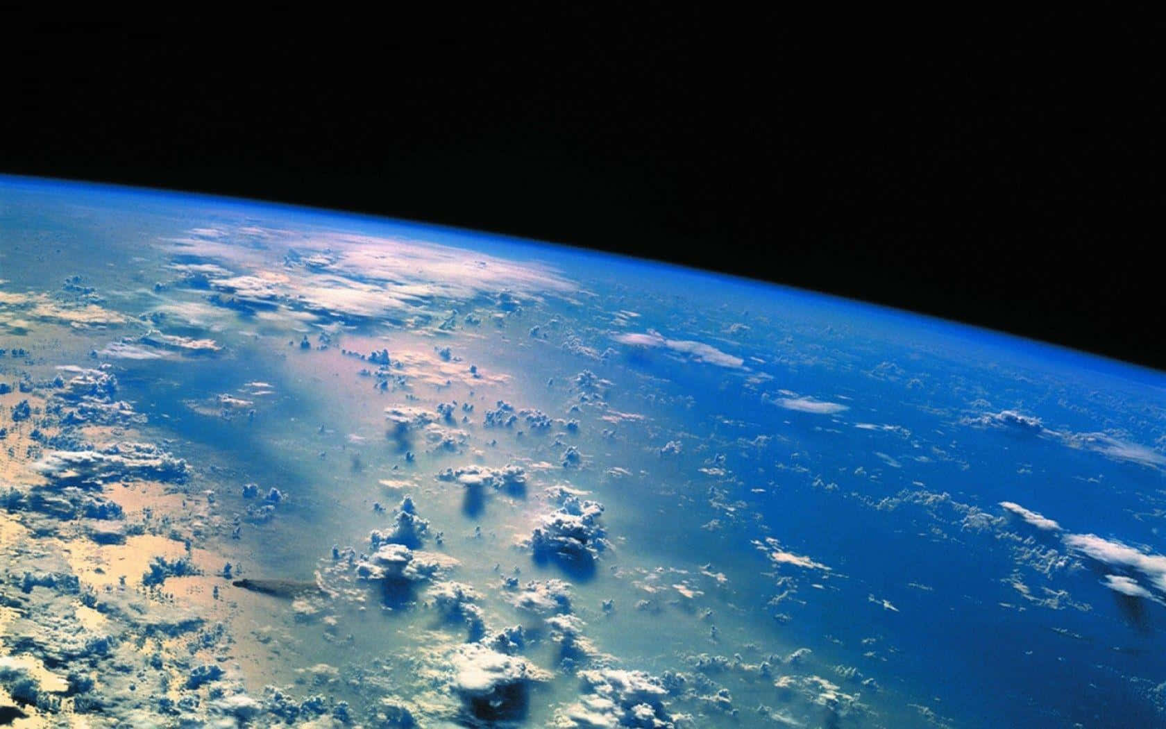 從外太空觀看的地球 壁紙 — 從太空俯瞰地球的壯麗景色，展現了旋轉的藍色海洋、白色雲層以及黑色太空虛空中的彎曲地平線。