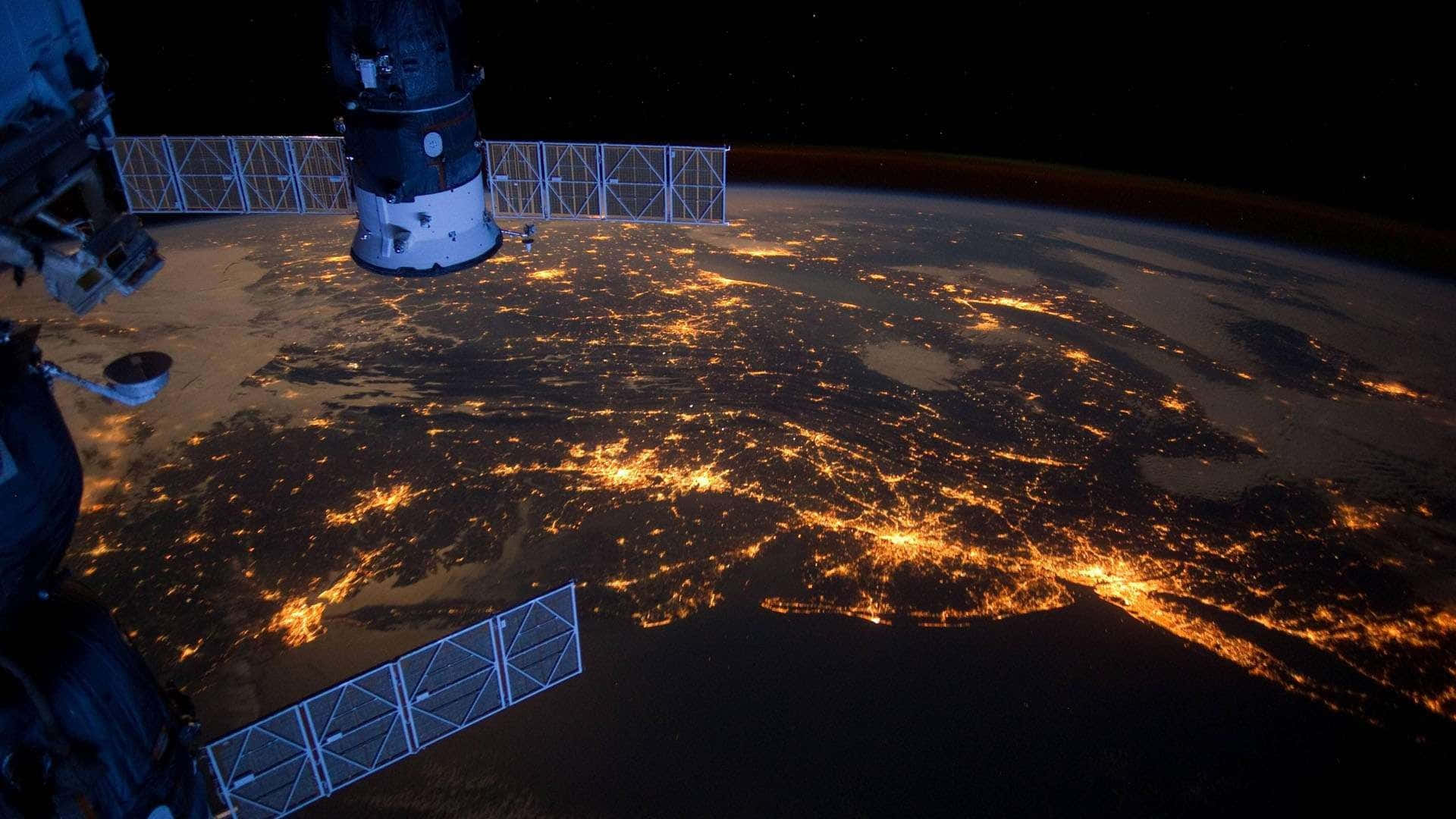 從太空在夜間看到的地球，發光的城市燈光和太空站結構可見。