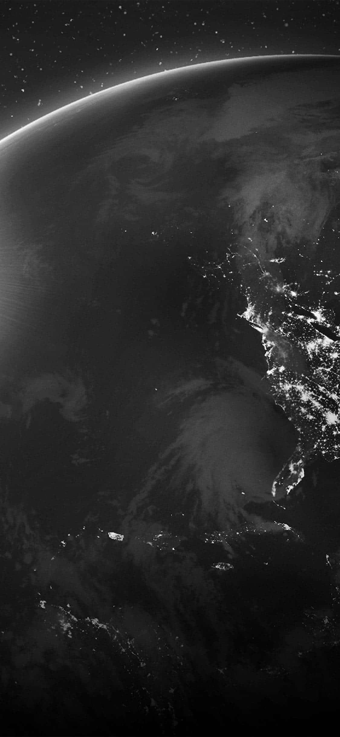 深色iPhone壁紙 桌布 壁紙 — 從太空俯瞰地球的黑白壯麗景象，展現了旋轉的雲層和沿海城市閃爍的燈光。