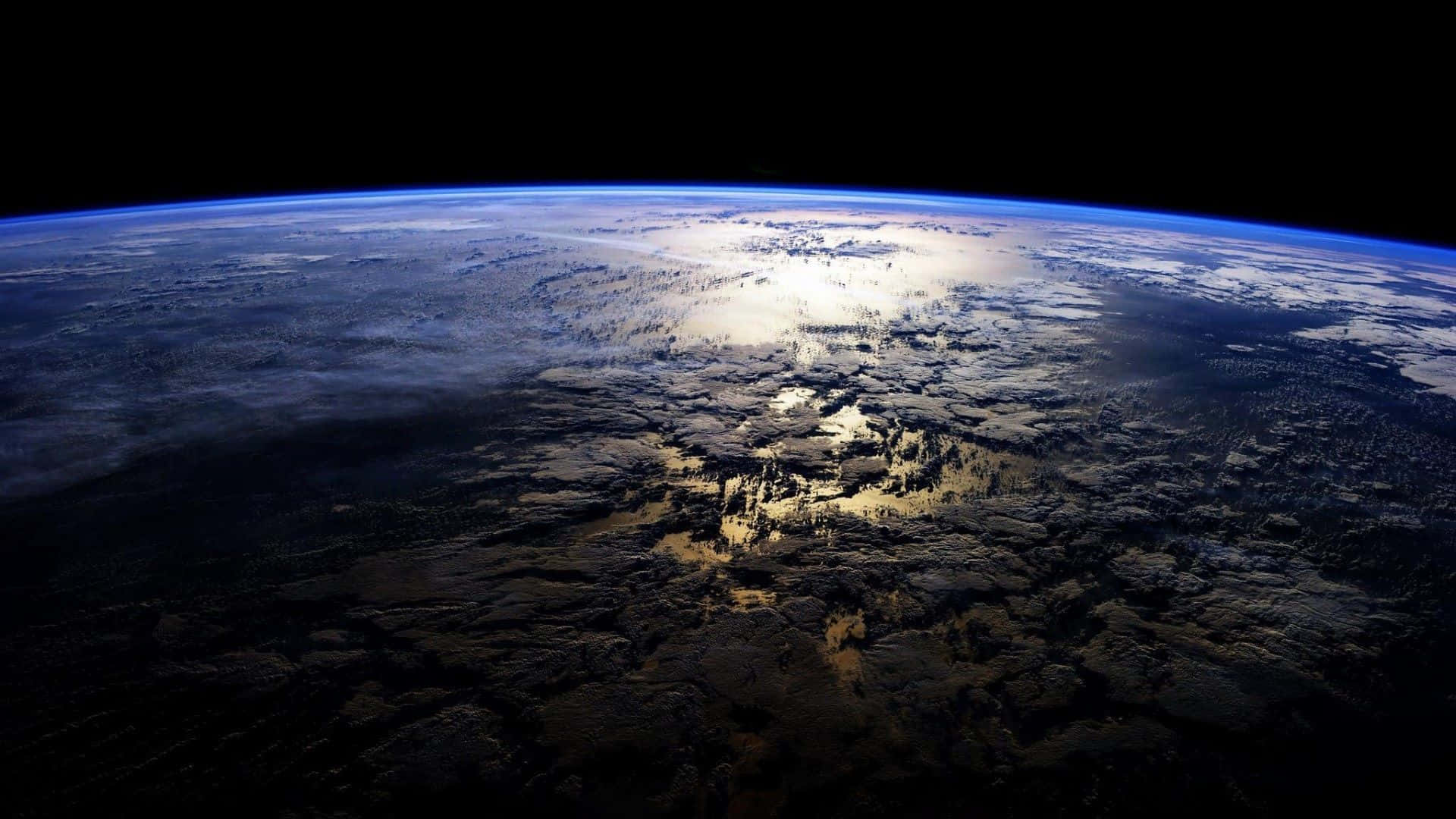 Atmosphere 桌布 壁紙 — 從太空看到的地球，帶有發光的藍色大氣層和黑暗陸地上旋轉的雲層。