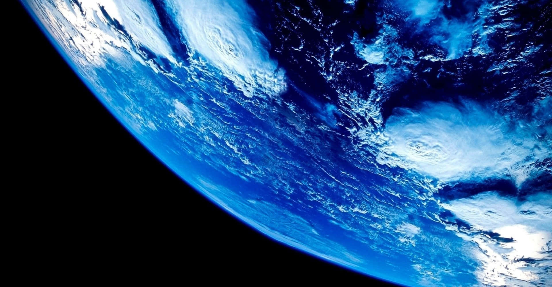 Blue Planet 桌布 壁紙 — 從太空看到的地球驚人彎曲景觀，展現出蔚藍海洋與白色雲層在黑色虛空中旋轉。