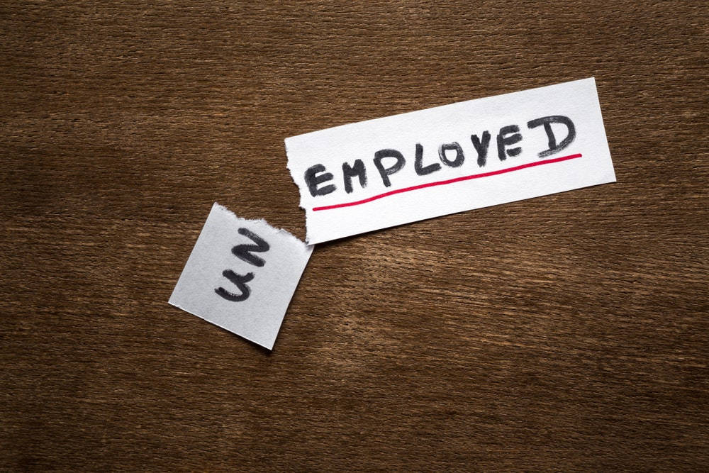 撕破的紙張上 'EMPLOYED' 被劃掉，撕口處露出 'UN'。