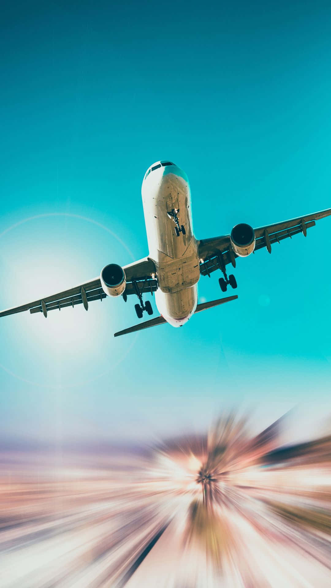 從小型飛機俯瞰滑雪度假村入口 壁紙 — 一架商用飛機在充滿活力的藍綠色天空中翱翔，下方有太陽光線和動態模糊效果。