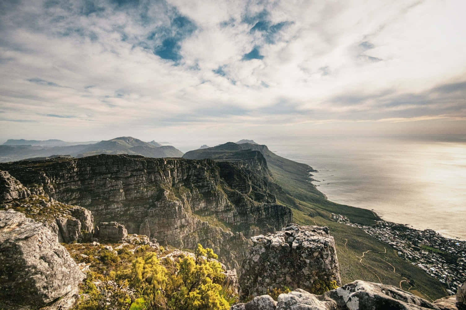 South Africa 桌布 壁紙 — 從岩石懸崖俯瞰沿海城鎮和海洋，天空部分多雲，景色令人嘆為觀止。