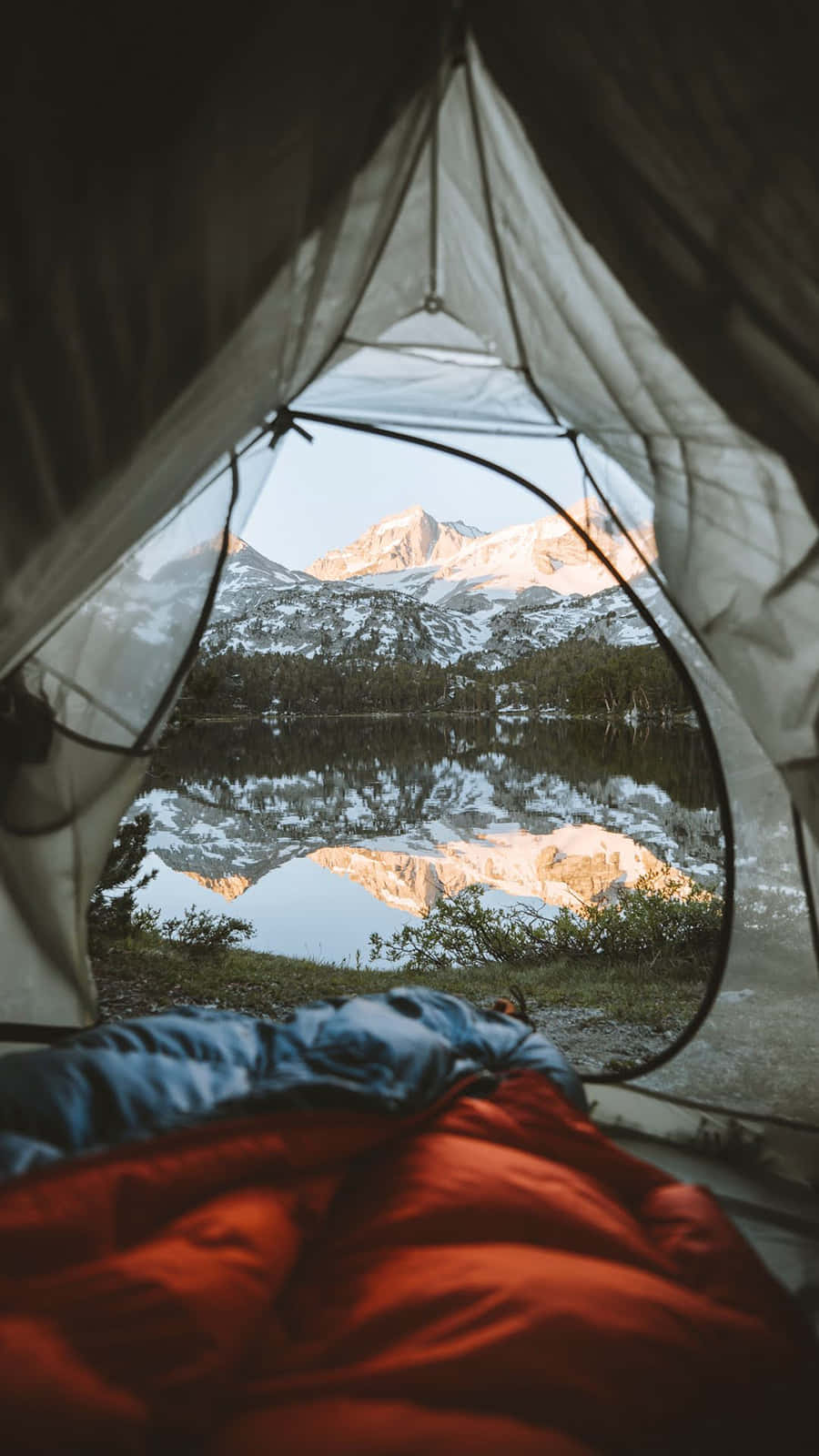 Camp 桌布 壁紙 — 從帳篷內望向日出時平靜湖面倒映著積雪覆蓋的山峰。
