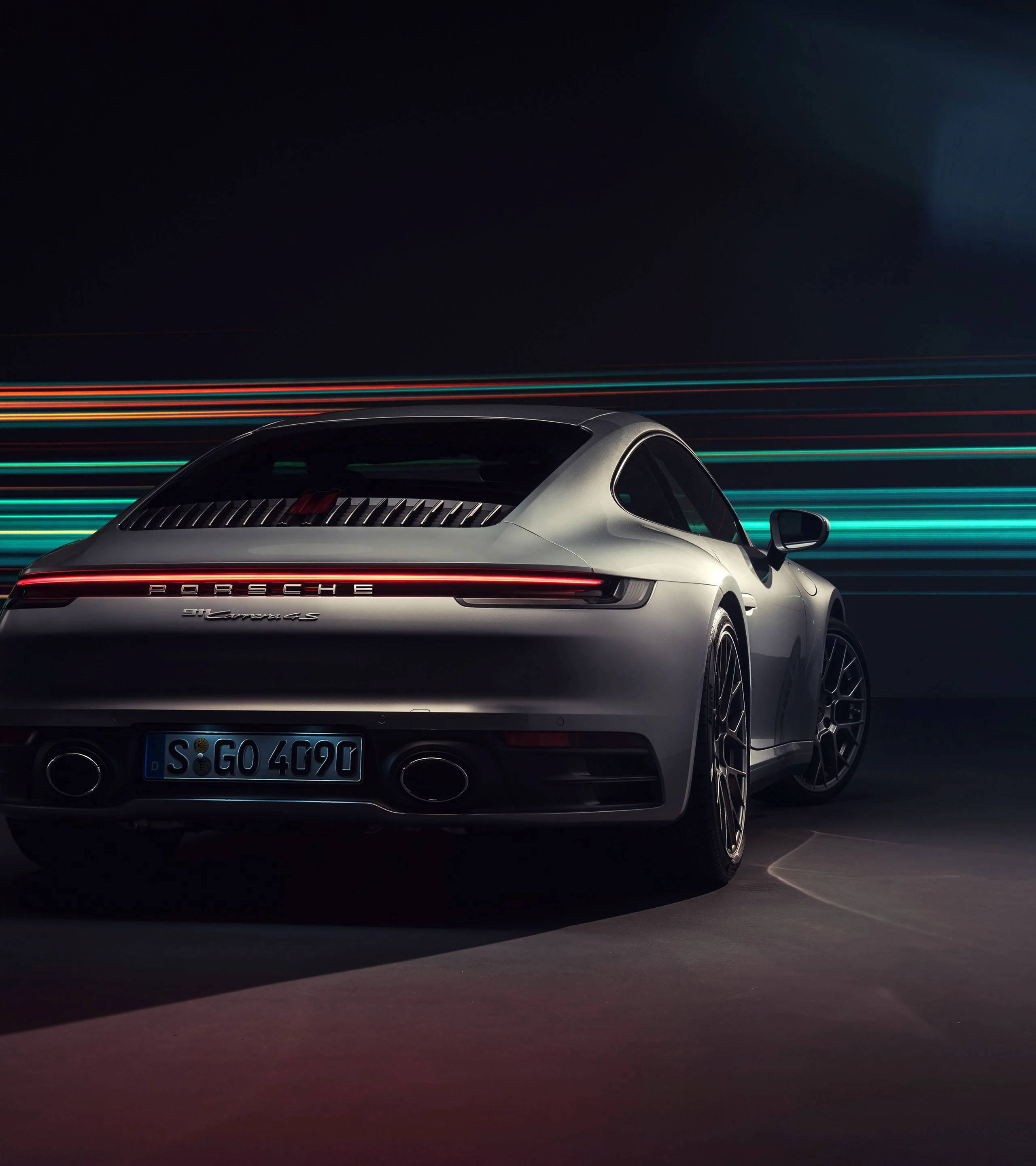 保時捷 桌布 壁紙 — 從後方觀看一輛時尚的銀色保時捷911 Turbo S，背景為帶有鮮豔霓虹燈軌跡的暗色背景。