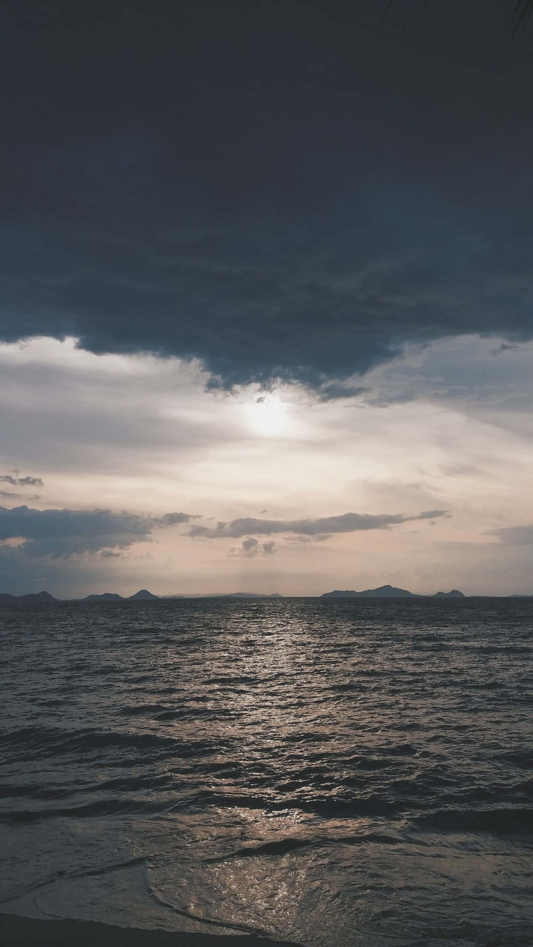 陽光穿透暴風雲，照耀在黑暗的海洋和遠處的島嶼上。