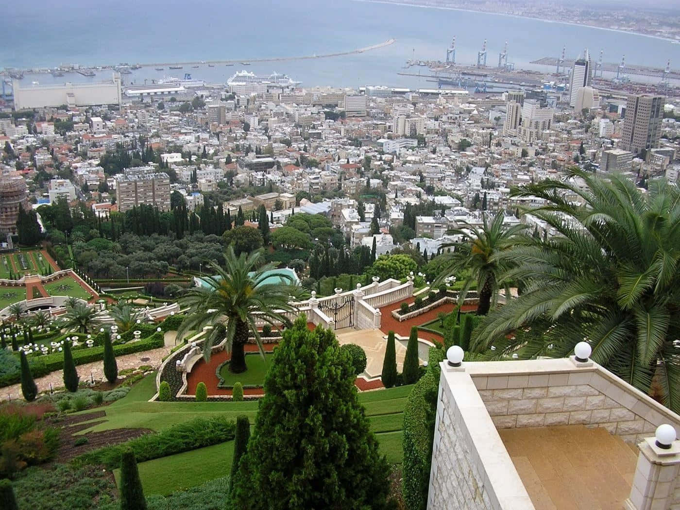 Israel 桌布 壁紙 — 從梯田花園俯瞰密集的海濱城市，下方有港口和船隻的廣闊景色。