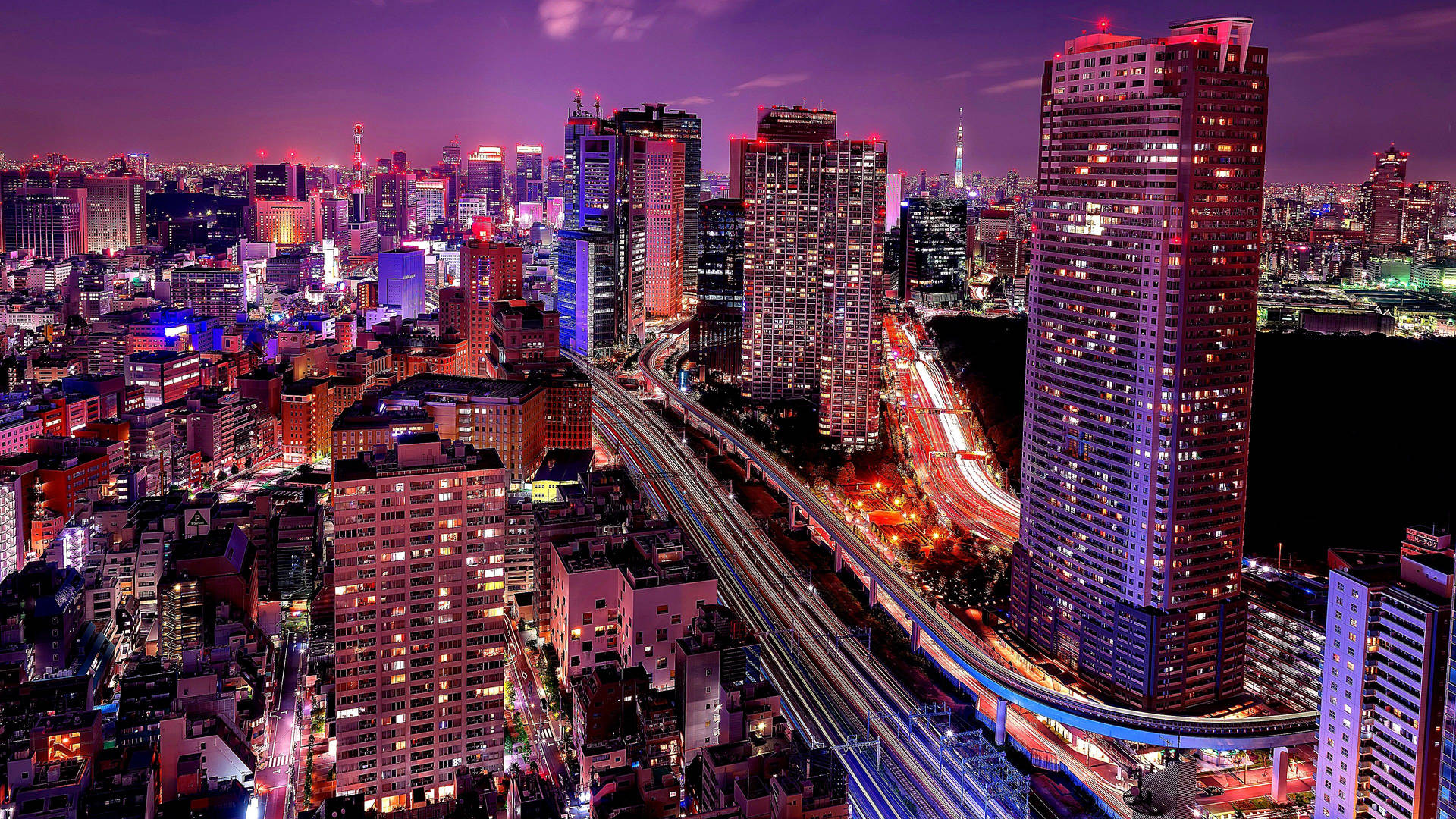 夜晚繁忙的城市，燈火通明的建築物和移動車輛的光軌。