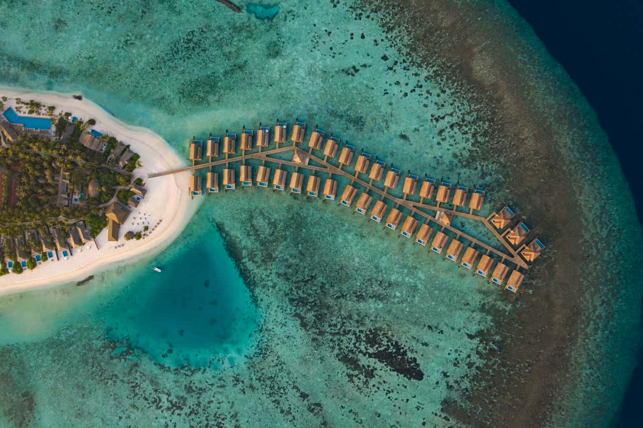 Maldives Island 桌布 壁紙 — 從白色沙灘島嶼延伸至碧綠潟湖水面的豪華水上平房鳥瞰圖。