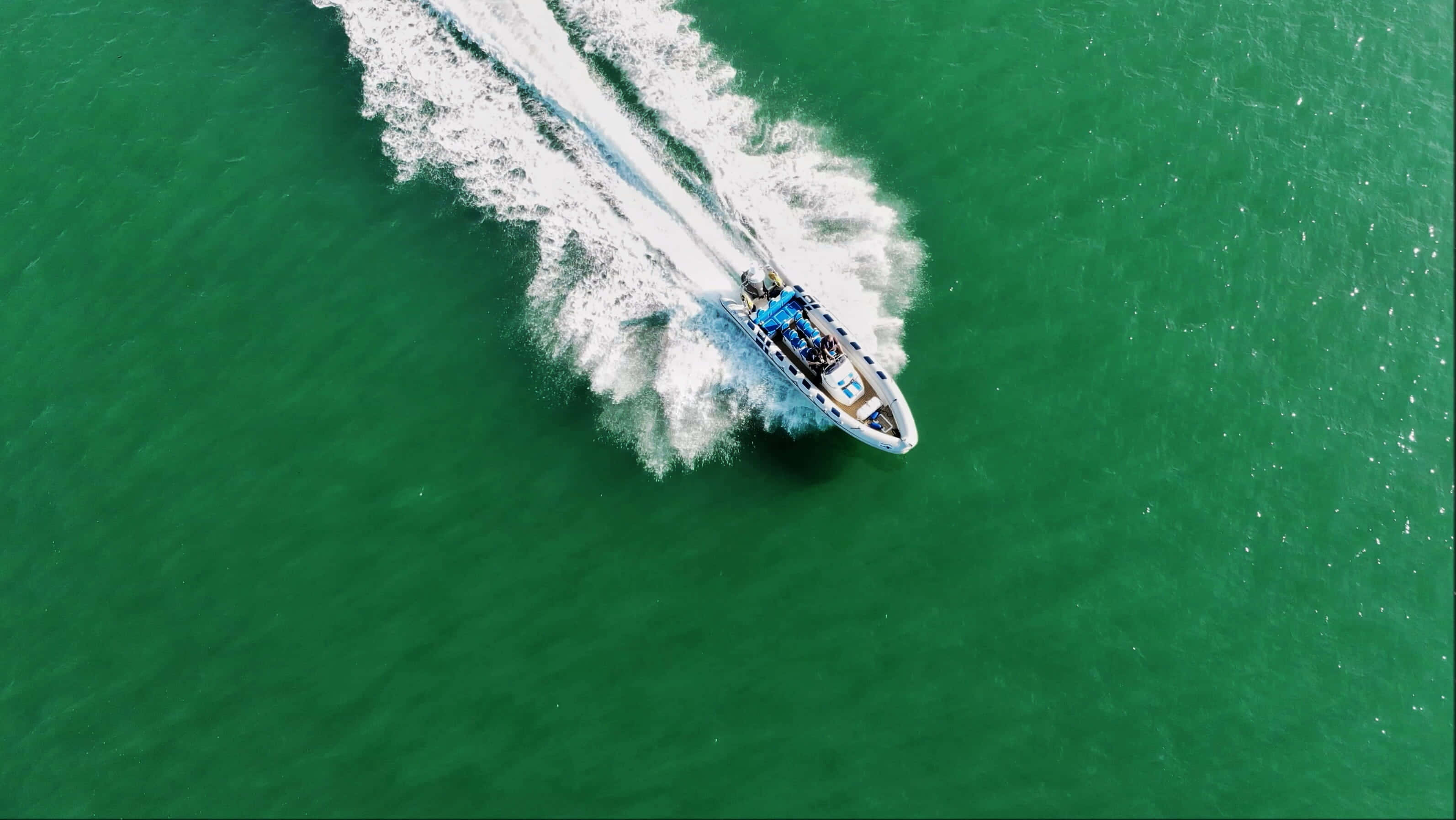 Boating 桌布 壁紙 — 從空中俯瞰，一艘快艇劃過翠綠海水，留下白色泡沫尾跡。