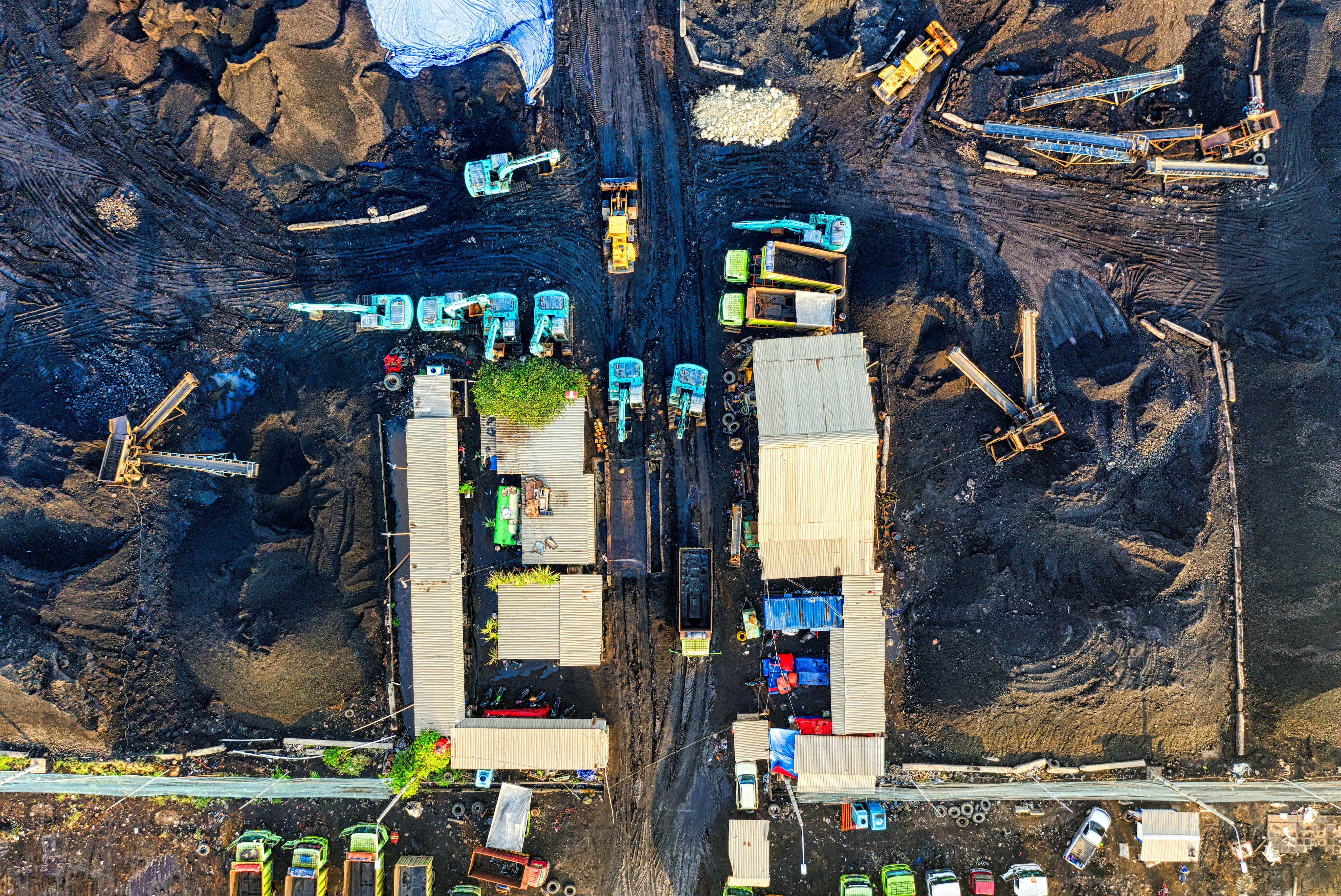 Mining 桌布 壁紙 — 從空中俯瞰一個廣闊的煤礦，重型機械和輸送帶在黑暗的泥土和臨時建築物之間。