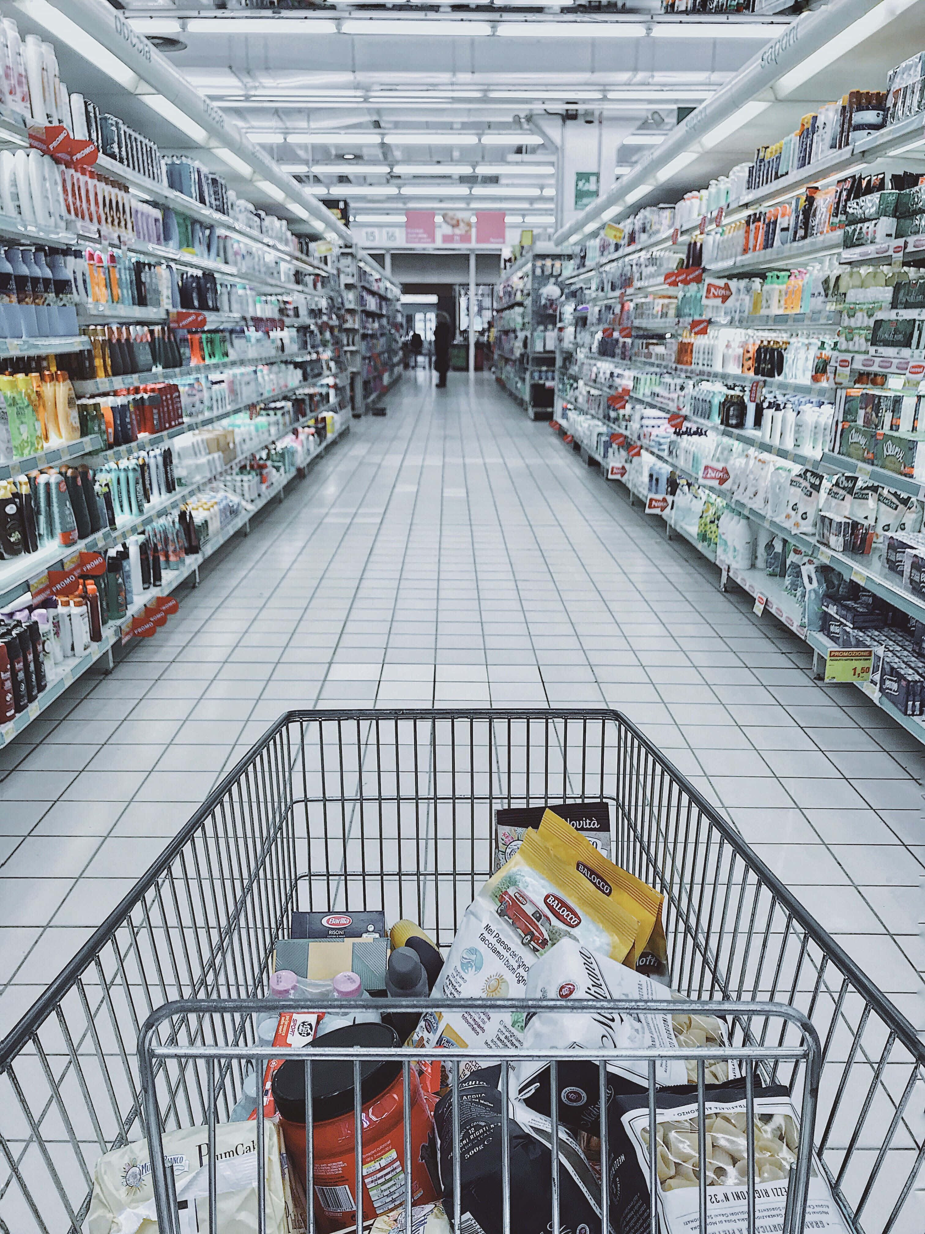 Grocery Store 桌布 壁紙 — 從裝滿雜貨的購物車中，以第一人稱視角穿梭於燈光明亮的超市通道。